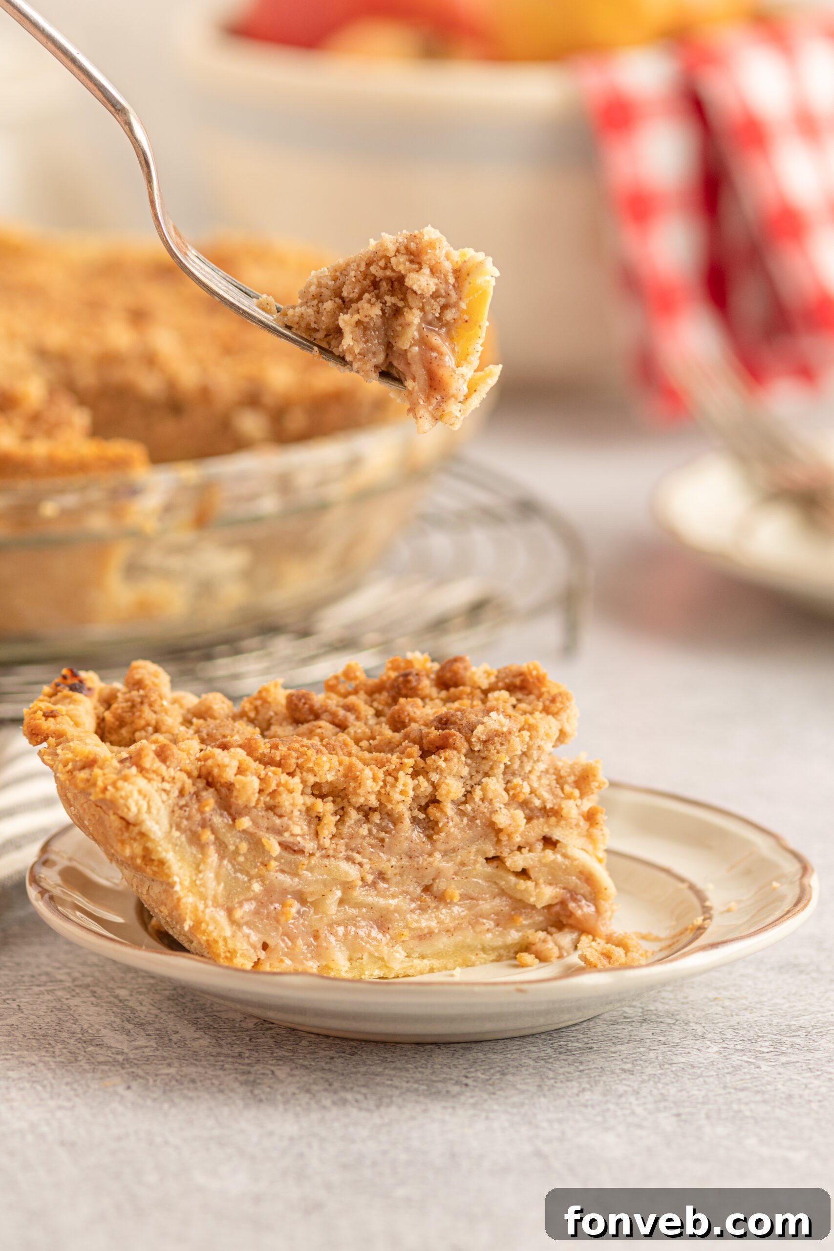 Golden Dutch Apple Crumb Delight 5 A piece of Dutch apple pie on a tan plate with a piece being removed with a silver fork.
