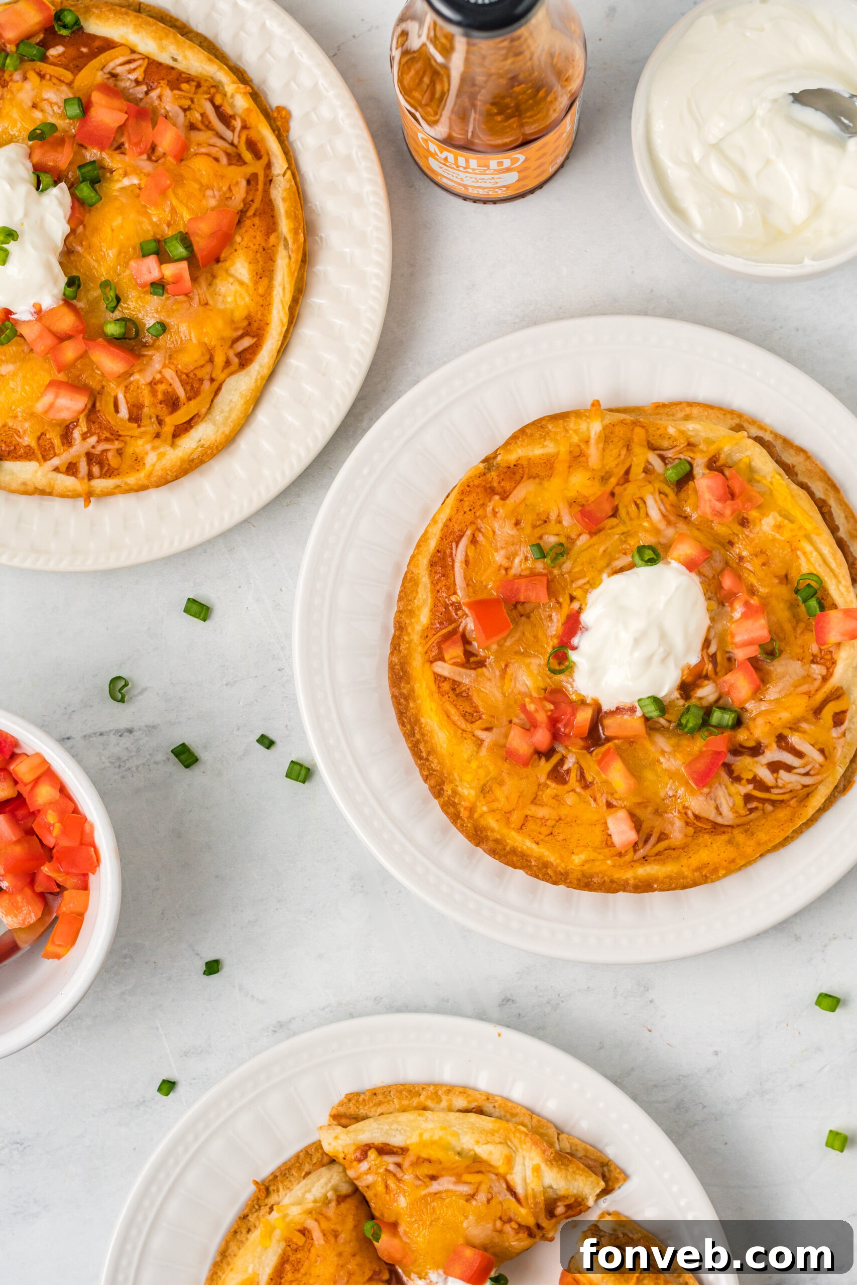 Overhead shot of three Mexican pizzas on white plates. 
