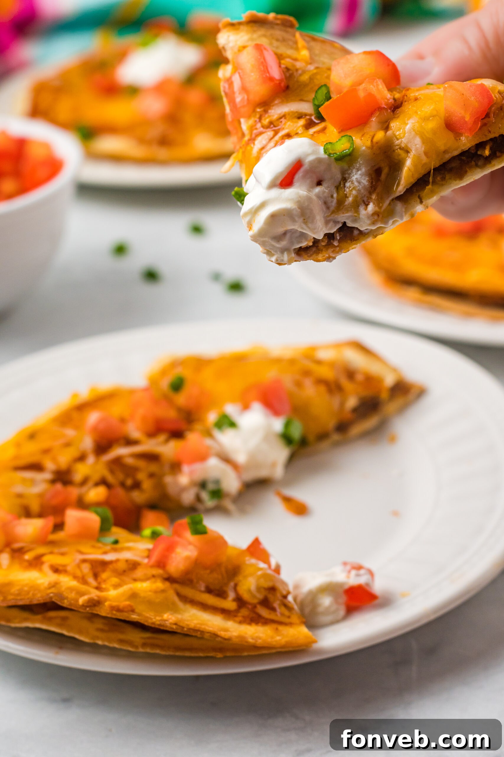 Close up of a piece of pizza being removed from a white plate. 