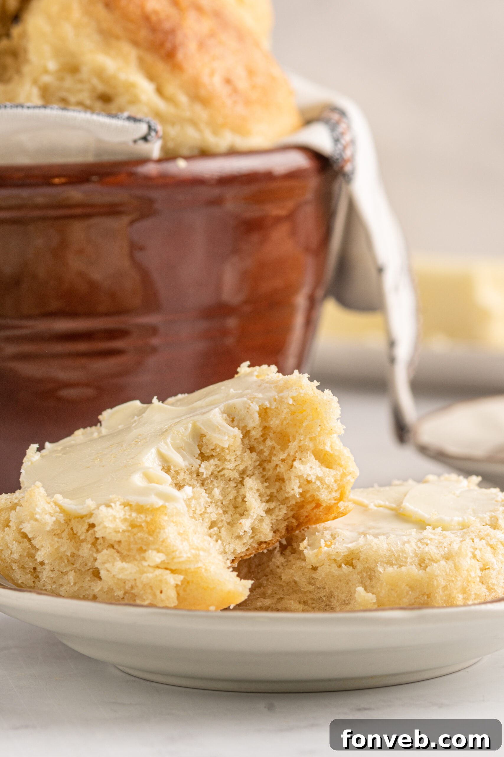 An Angel Biscuit sliced in half, revealing its fluffy interior, generously topped with melting butter.