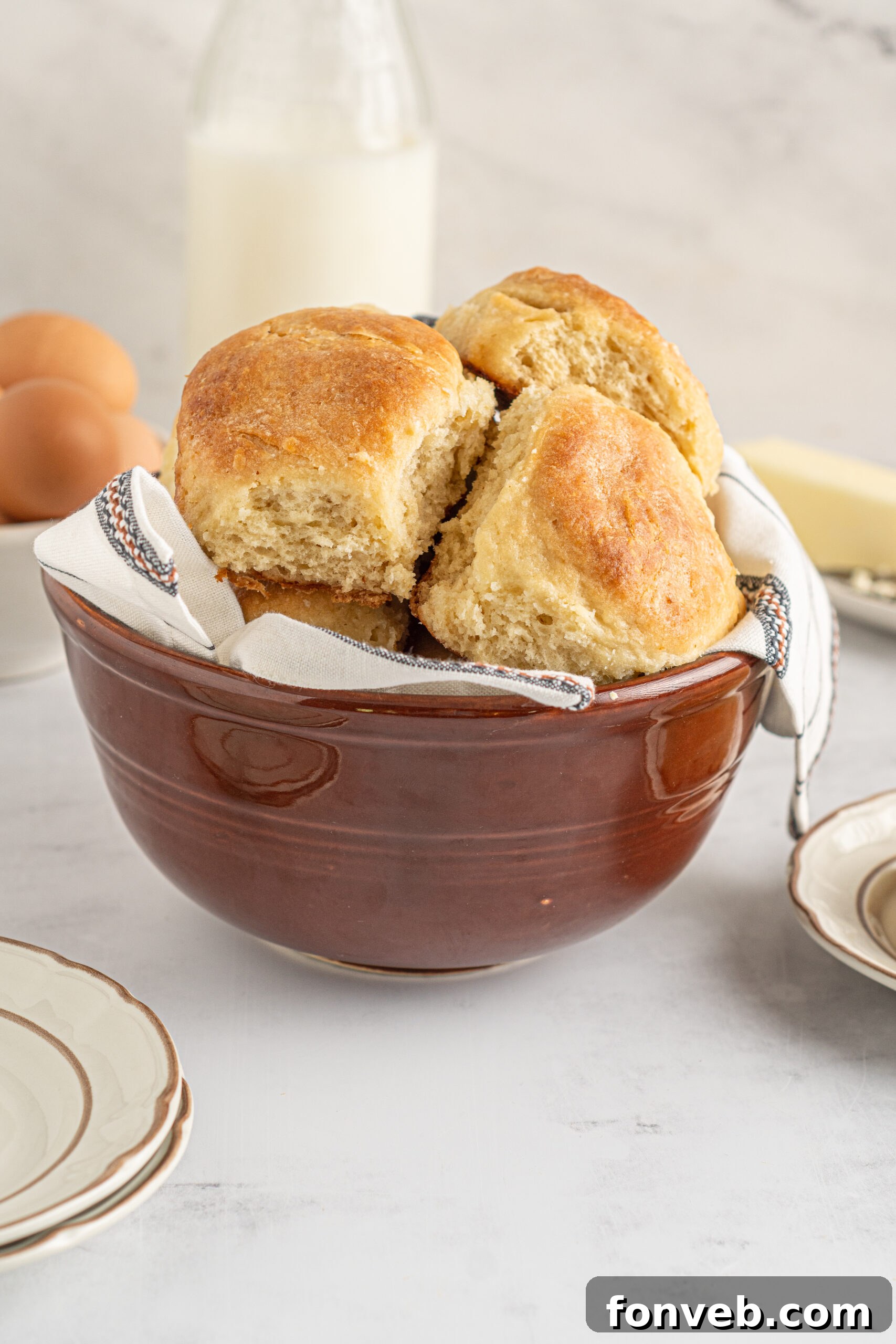 A vibrant red bowl overflowing with golden-brown Angel Biscuits, showcasing their appetizing color and inviting texture.