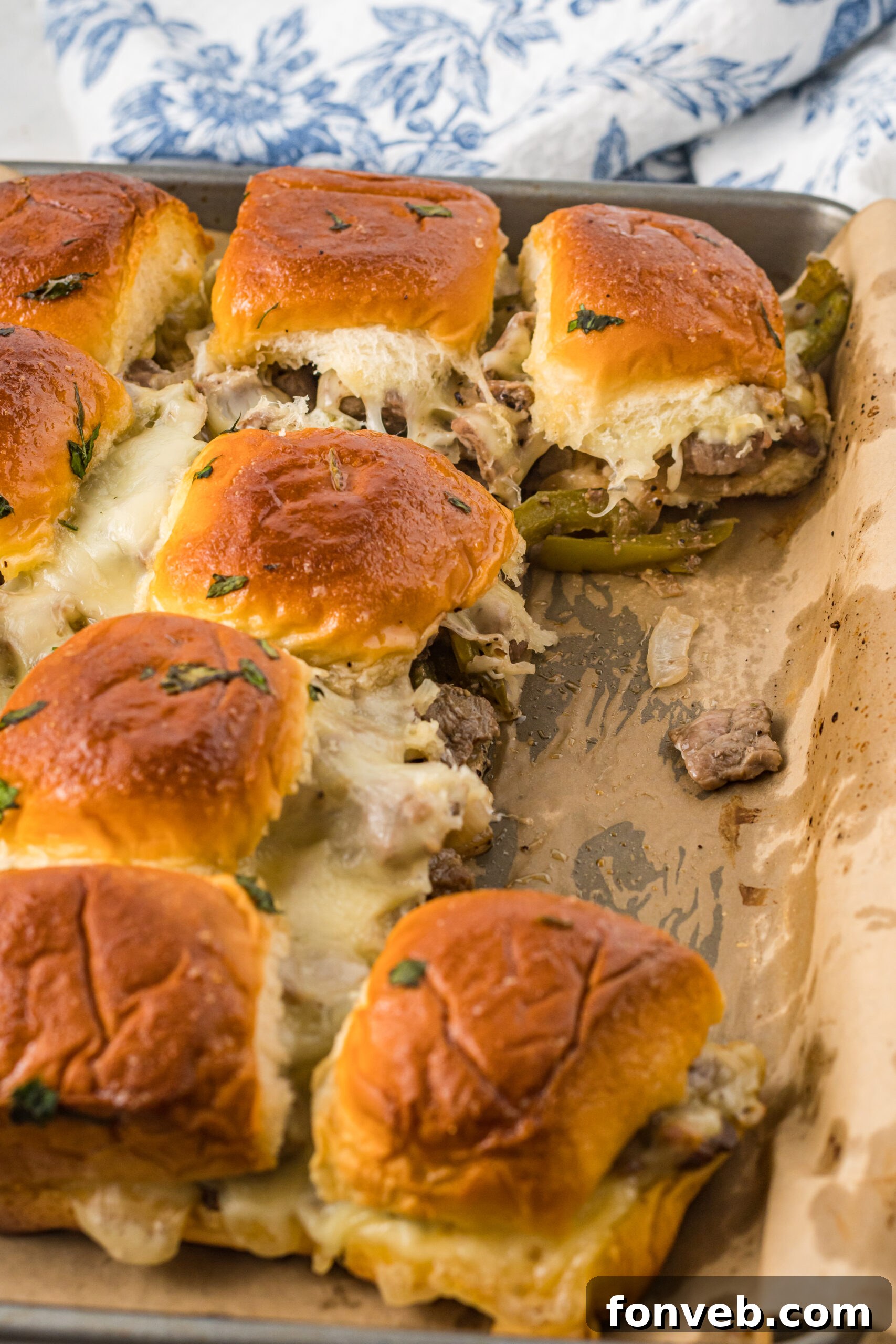 Ultimate Philly Cheesesteak Sliders 3 Philly Cheesesteak Sliders on a baking sheet with two removed.