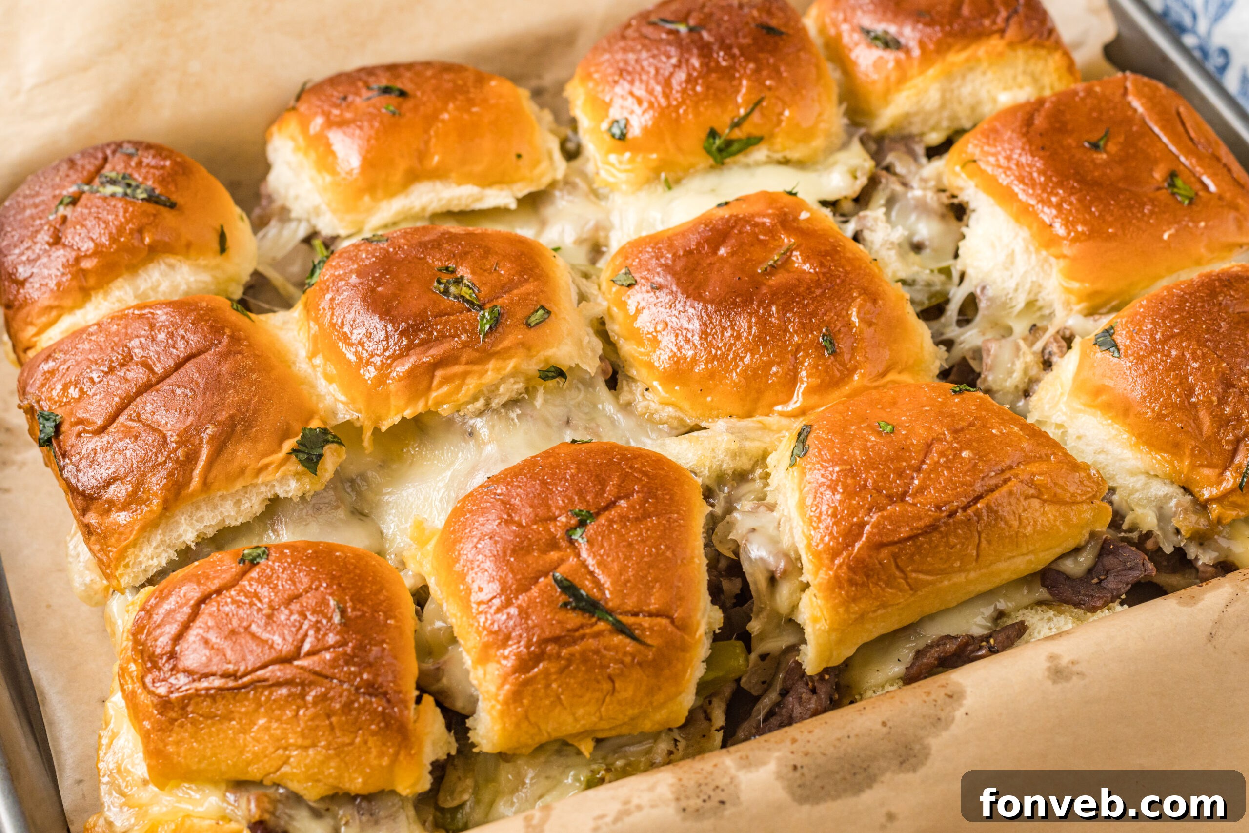 Ultimate Philly Cheesesteak Sliders 9 Philly Cheesesteak Sliders on a baking sheet, oozing with melty cheese!
