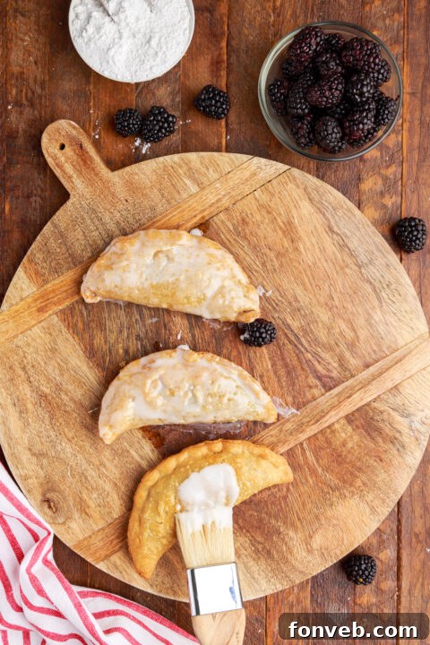 Overhead shot of brushing the glaze on top of the blackberry hand pies.