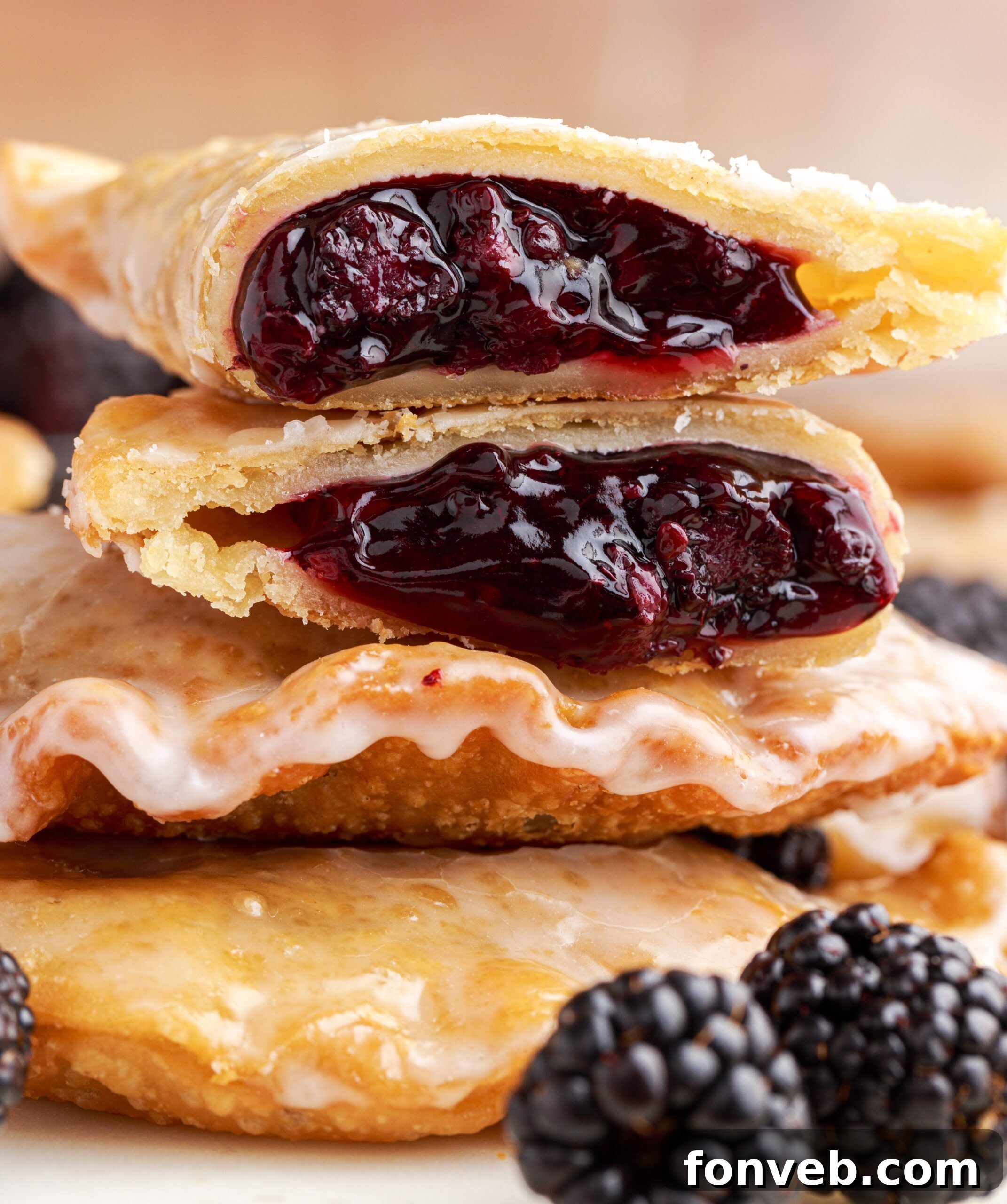 A blackberry hand pie cut in half and stacked on top of two other pies showing the berry filling.