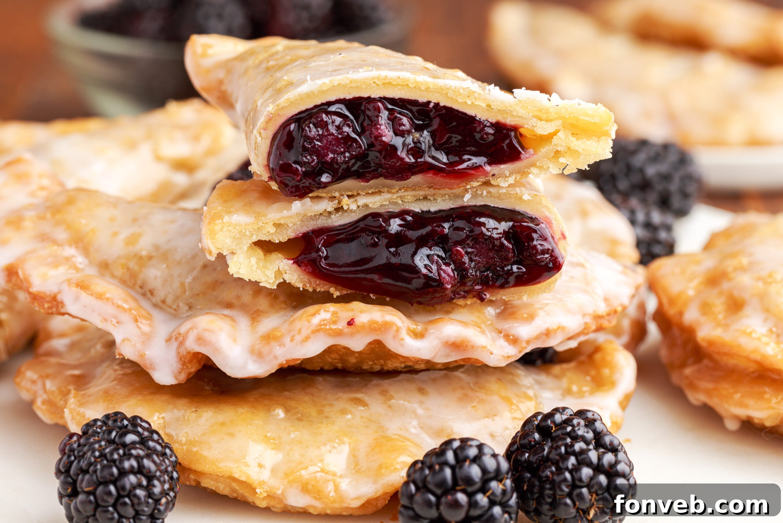 A blackberry hand pie cut in half and stacked on top of two other pies showing the berry filling.