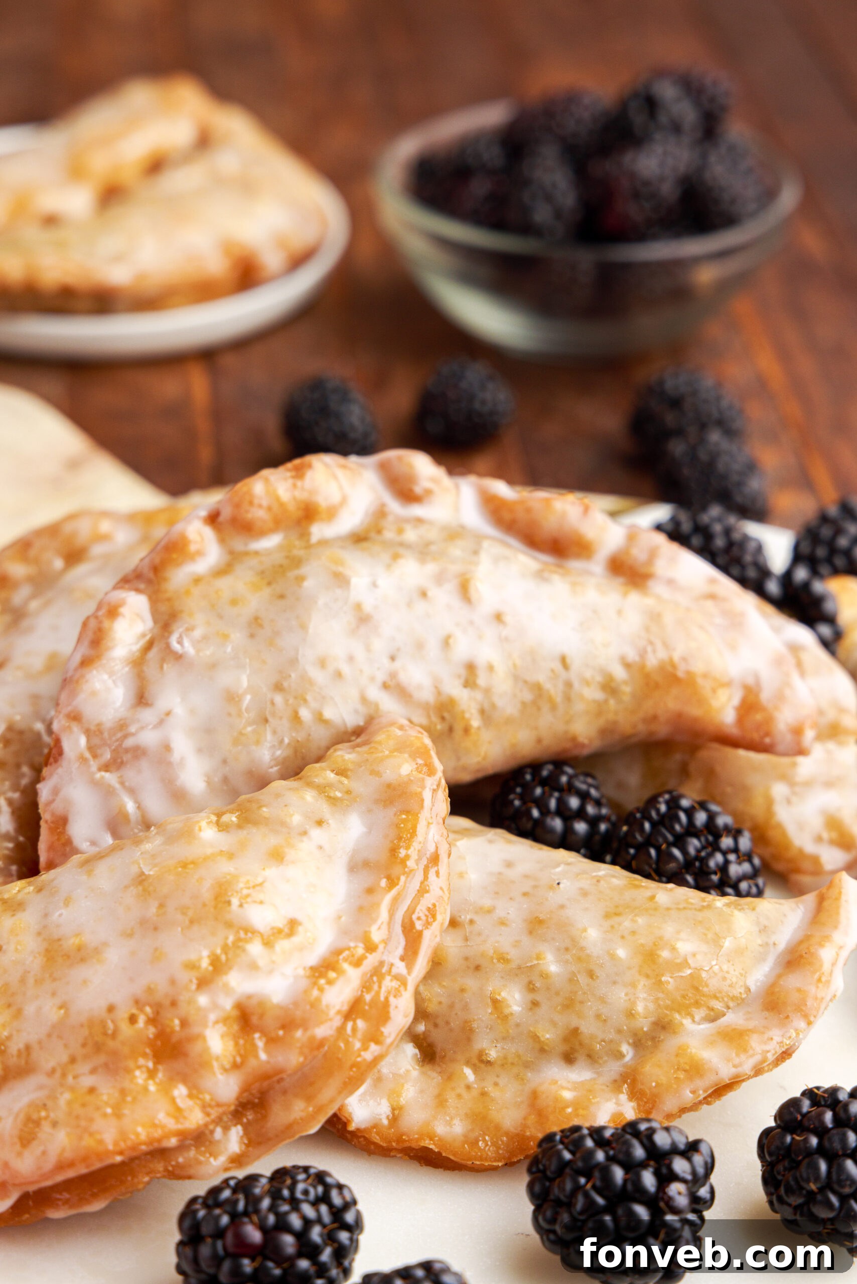 Hand pies stacked on a marble serving tray with fresh blackberries.