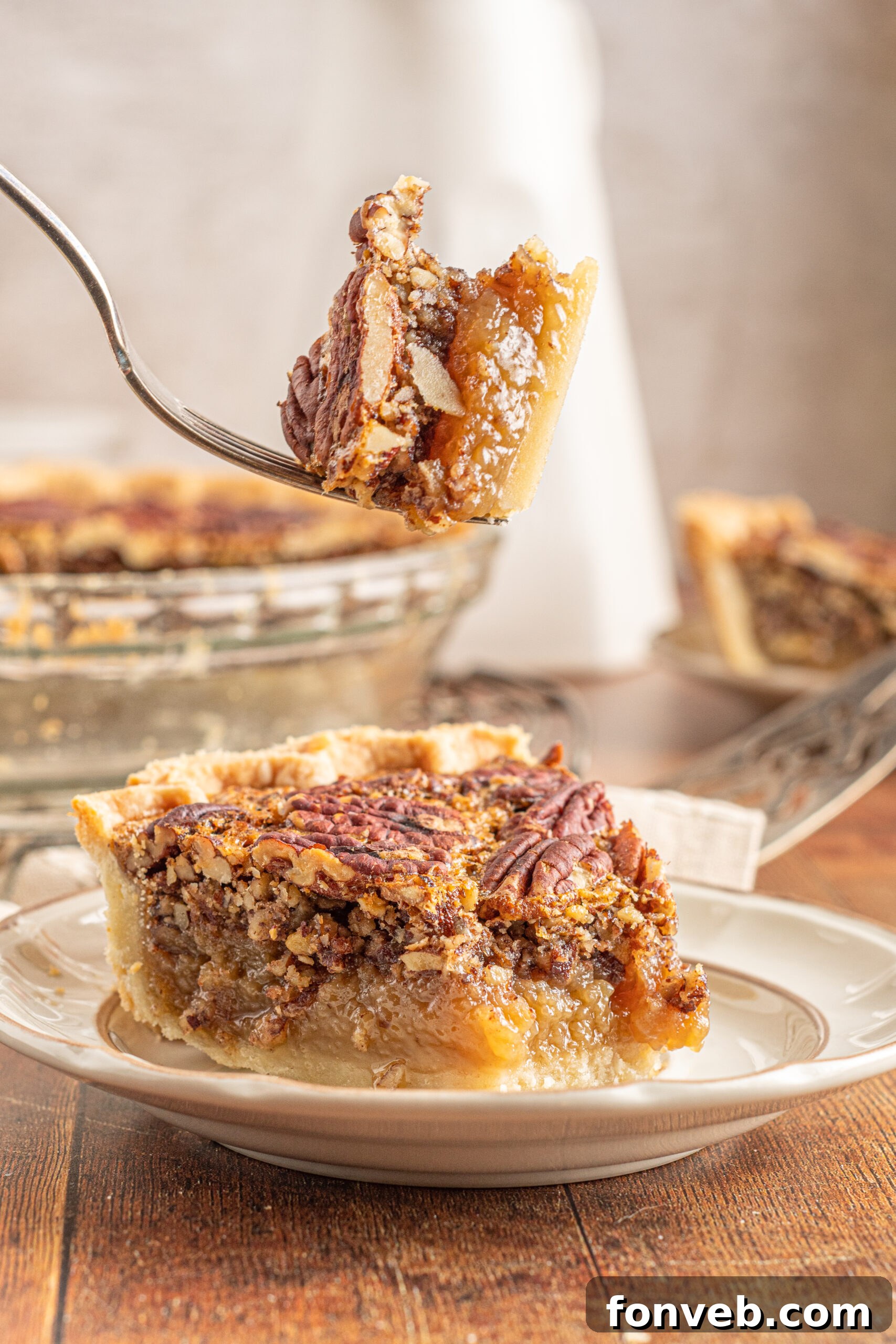 Bourbon Pecan Indulgence 13 A piece of pecan pie on a tan and brown plate with a bite of pie being removed with a silver fork.