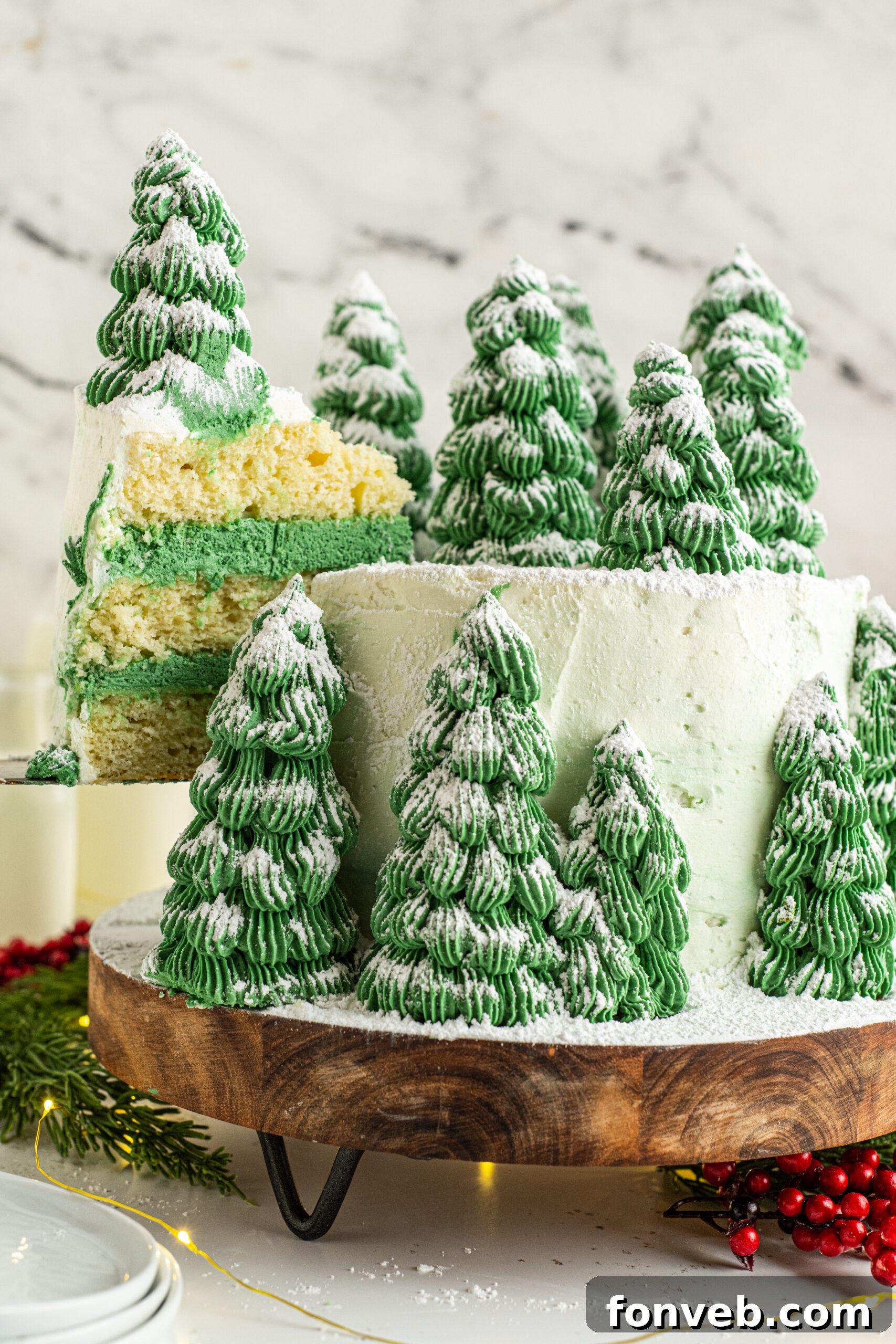 Christmas tree cake on a wooden serving board with a piece being removed showing the white and green layers inside. 