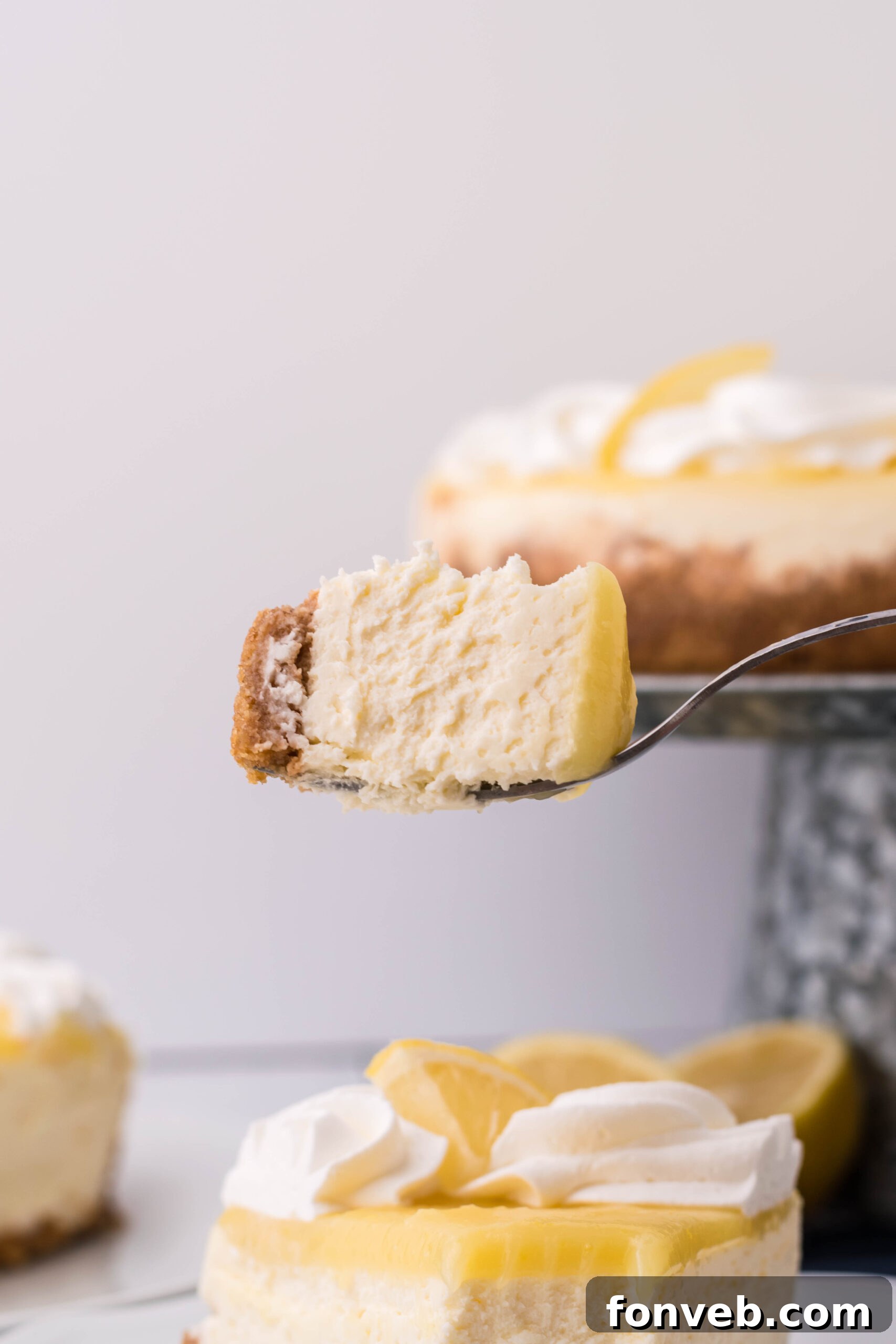 A bite of cheesecake being held up with a silver spoon showing the distinct three layers.