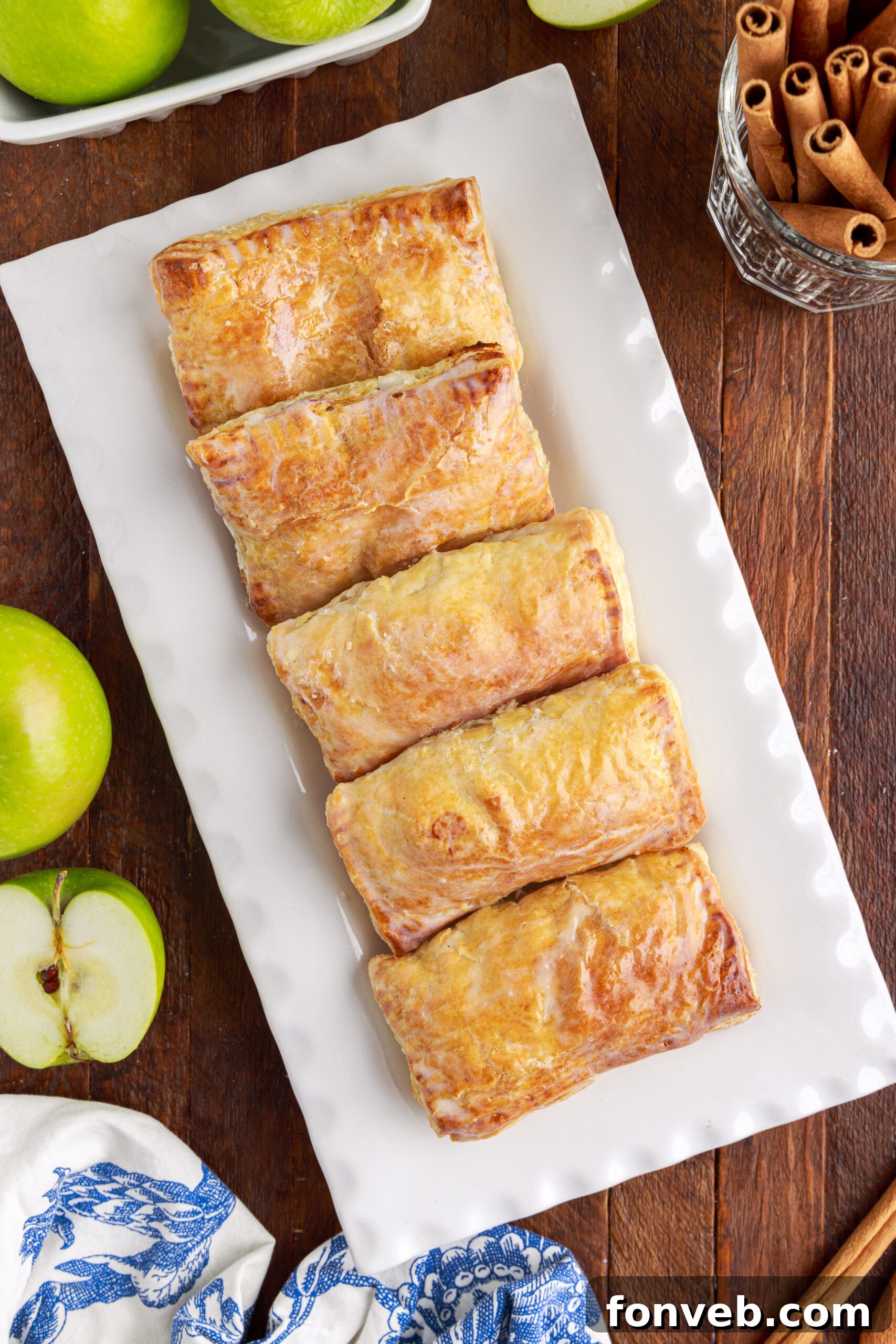Overhead view of six apple hand pies on a white serving platter. 