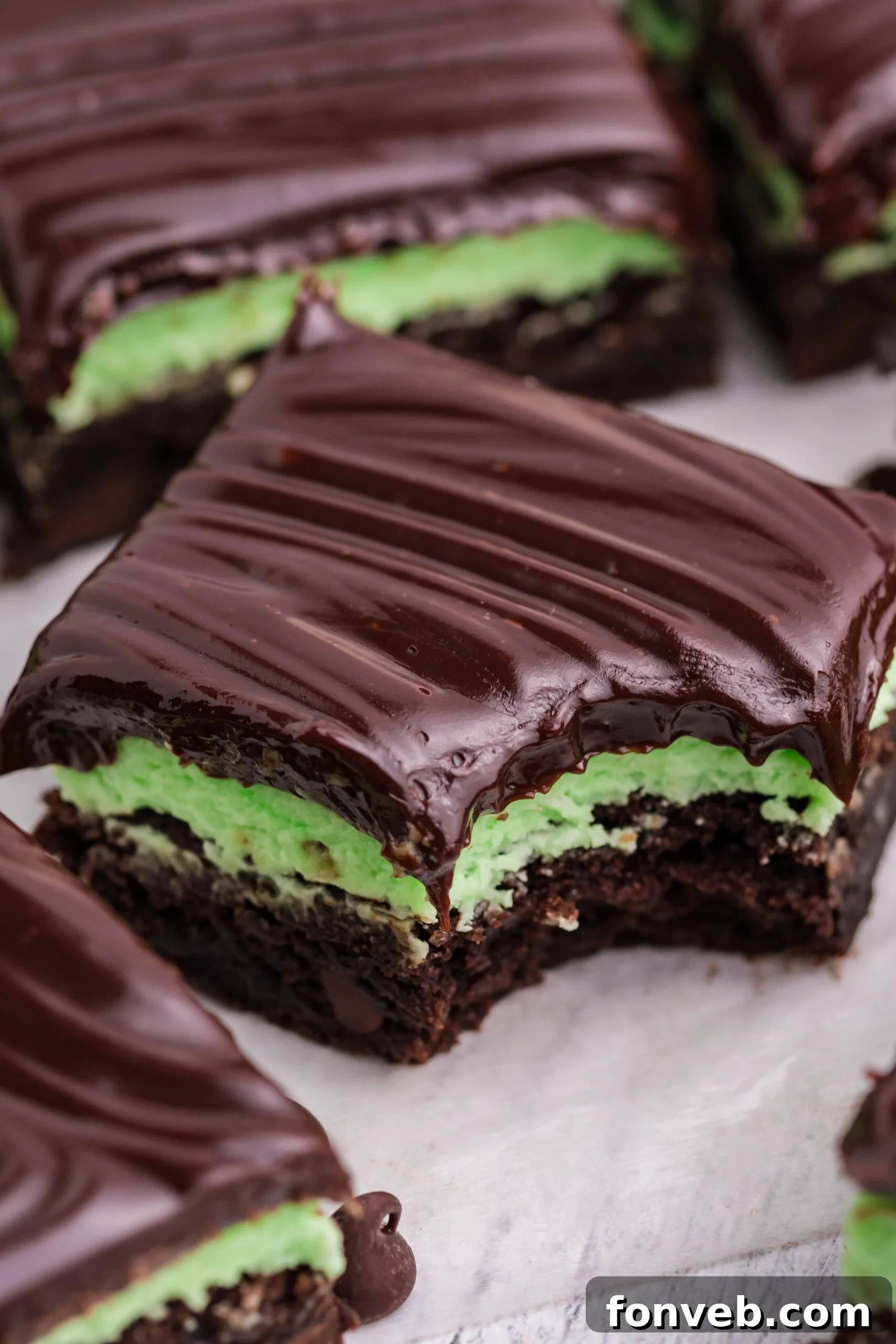 A bite removed from a mint chocolate brownie showing the three different layers.