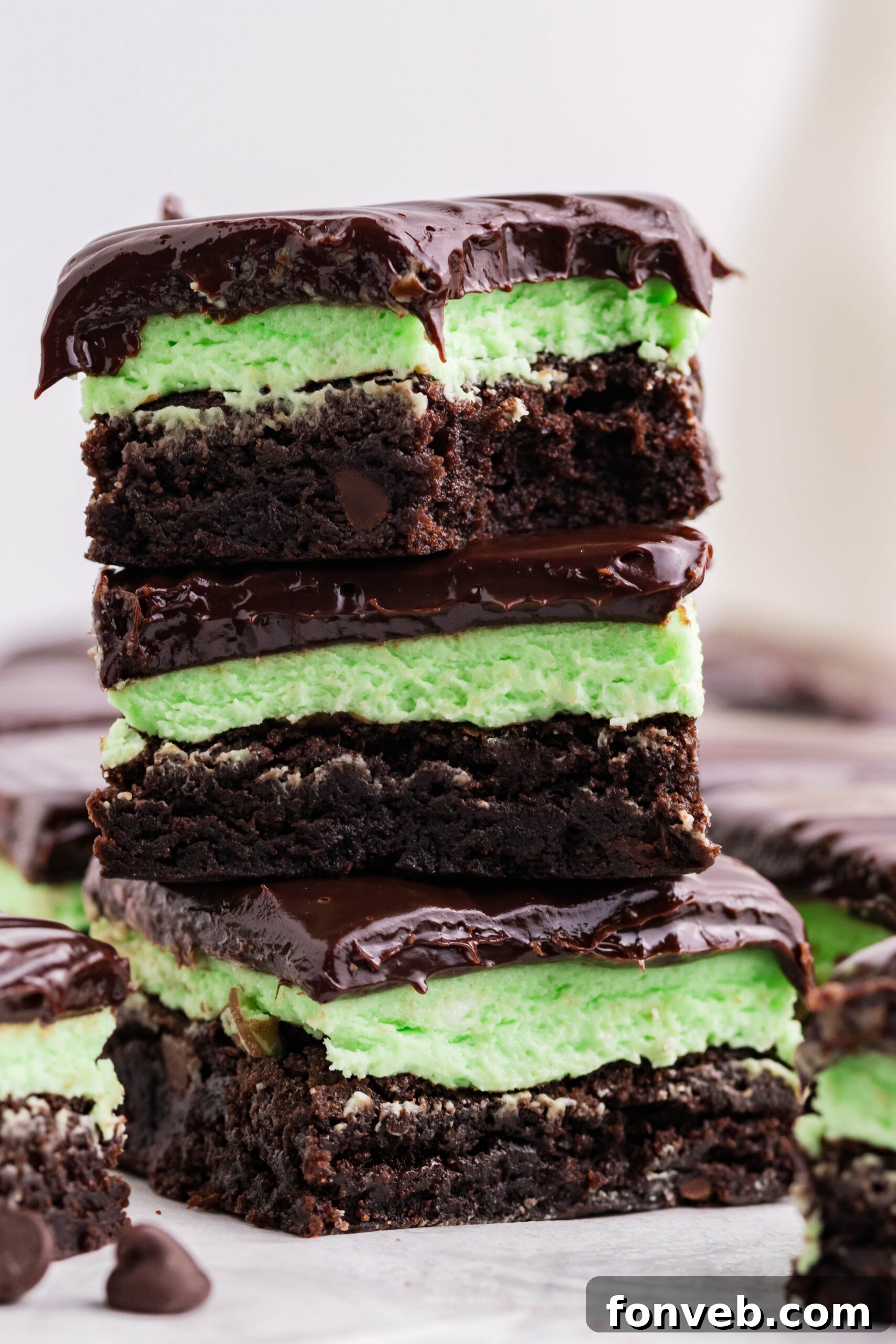 Three brownies stacked on top of each other with a bite removed from the top brownie.