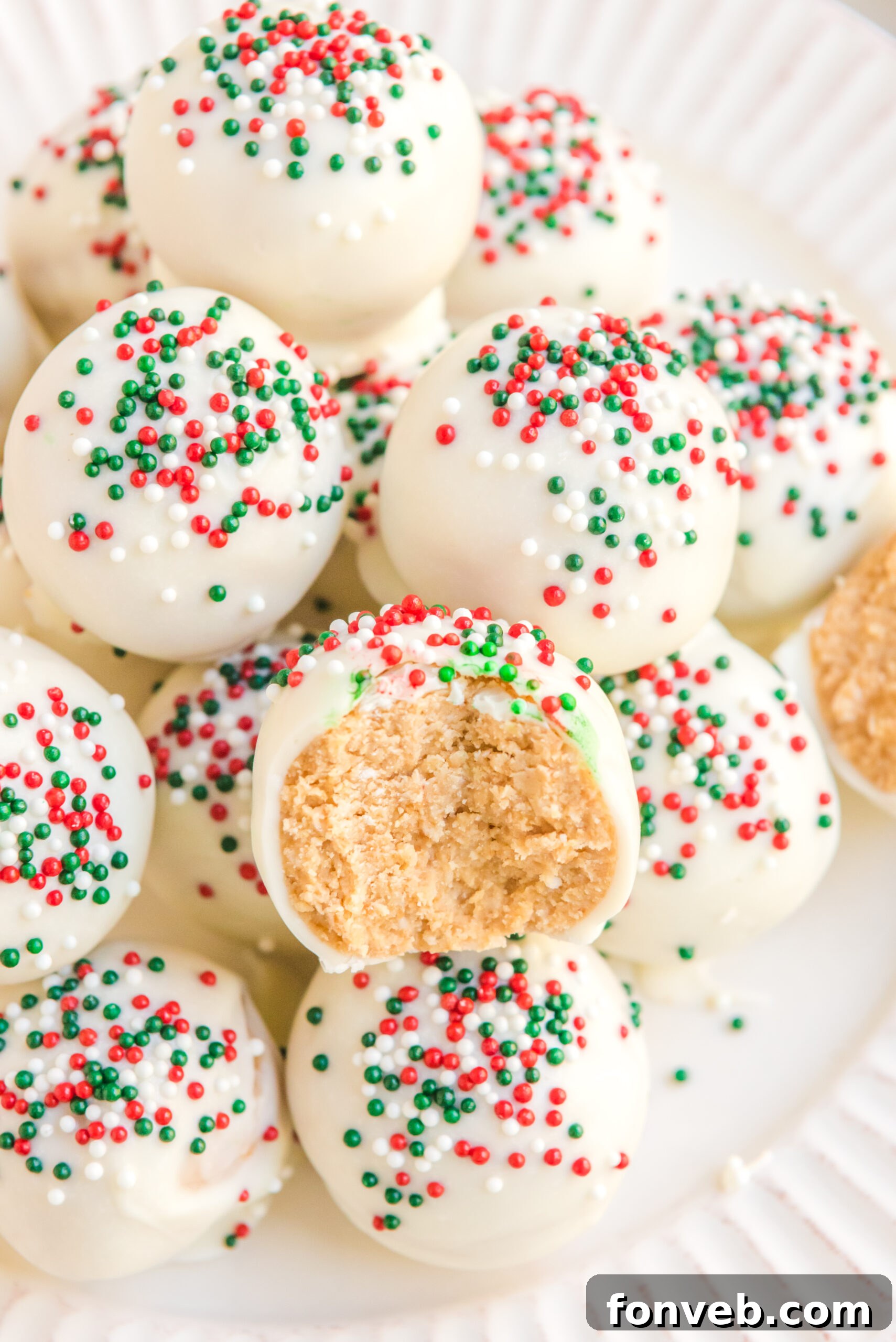 A White Chocolate Peanut Butter Snowball with a bite removed showing the inside on a white plate. 