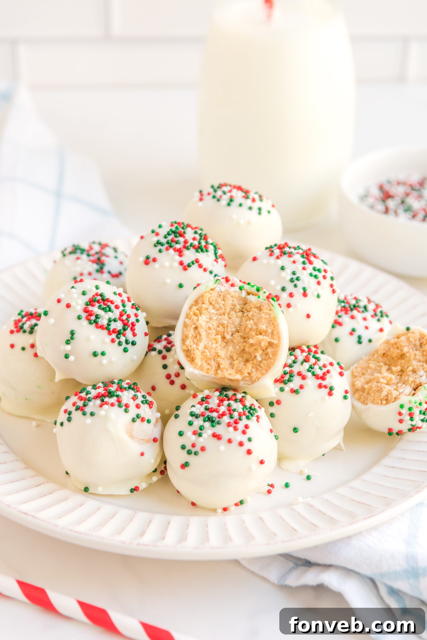 White Chocolate Truffles stacked on a white plate topped with red, white, and green sprinkles. 