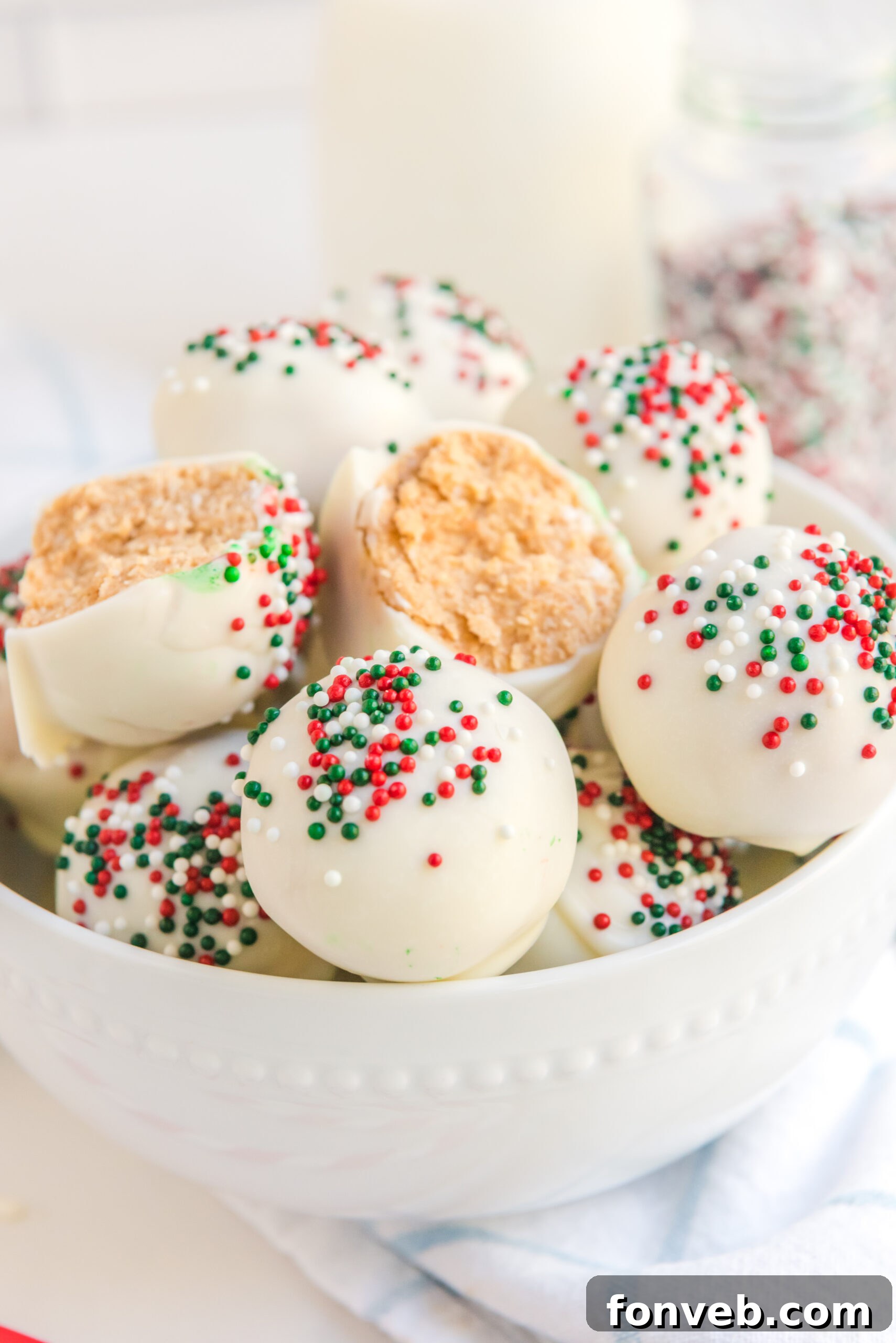 A White Chocolate Peanut Butter truffle cut in half stacked on more truffles in a white bowl. 