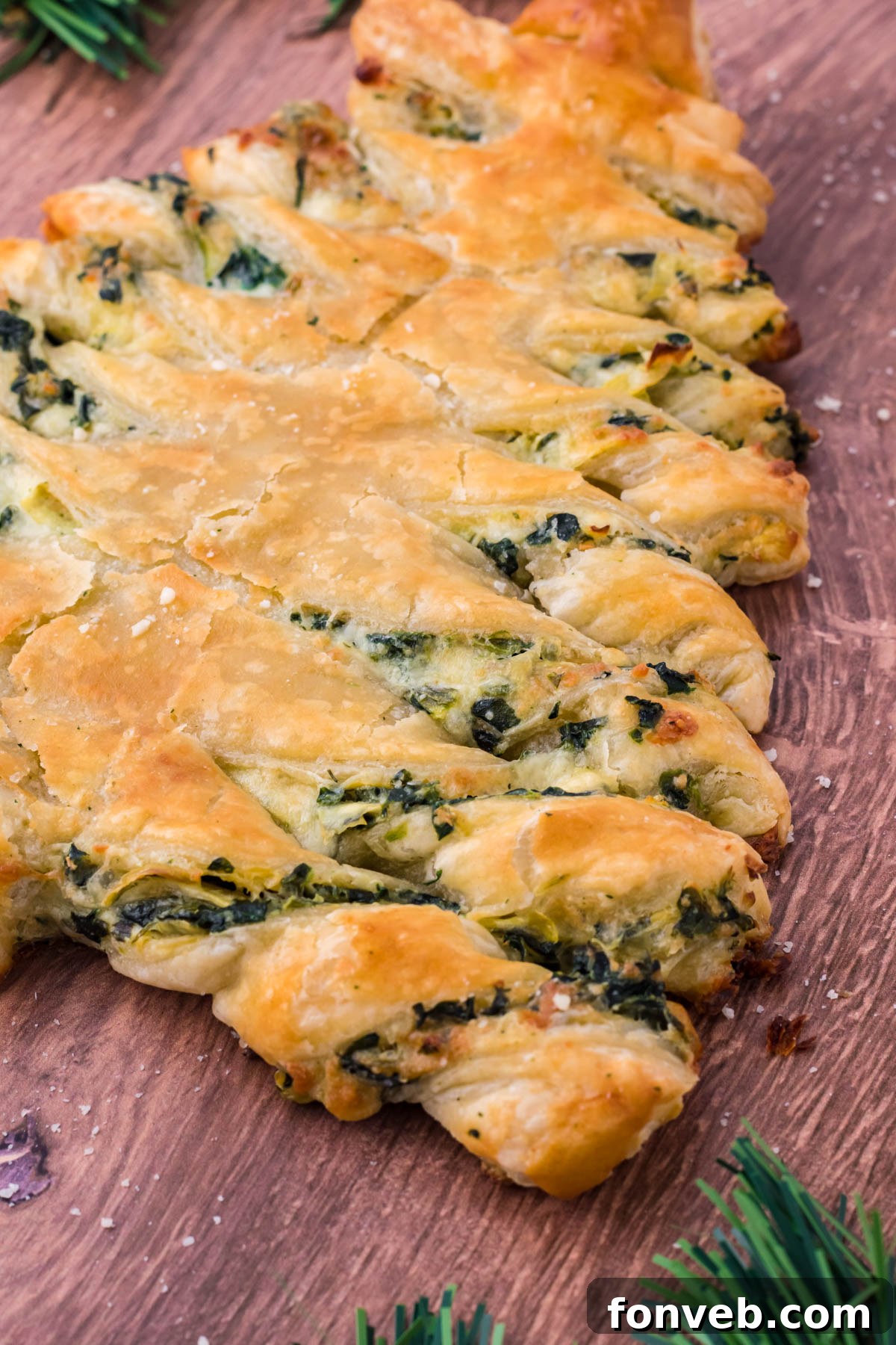 Tear and Share Christmas Spinach Artichoke Bread 3 Side view of the savory Spinach Artichoke Dip Pull Apart Christmas Tree Bread, showcasing its golden crust and twisted branches, set on a dark wood background.