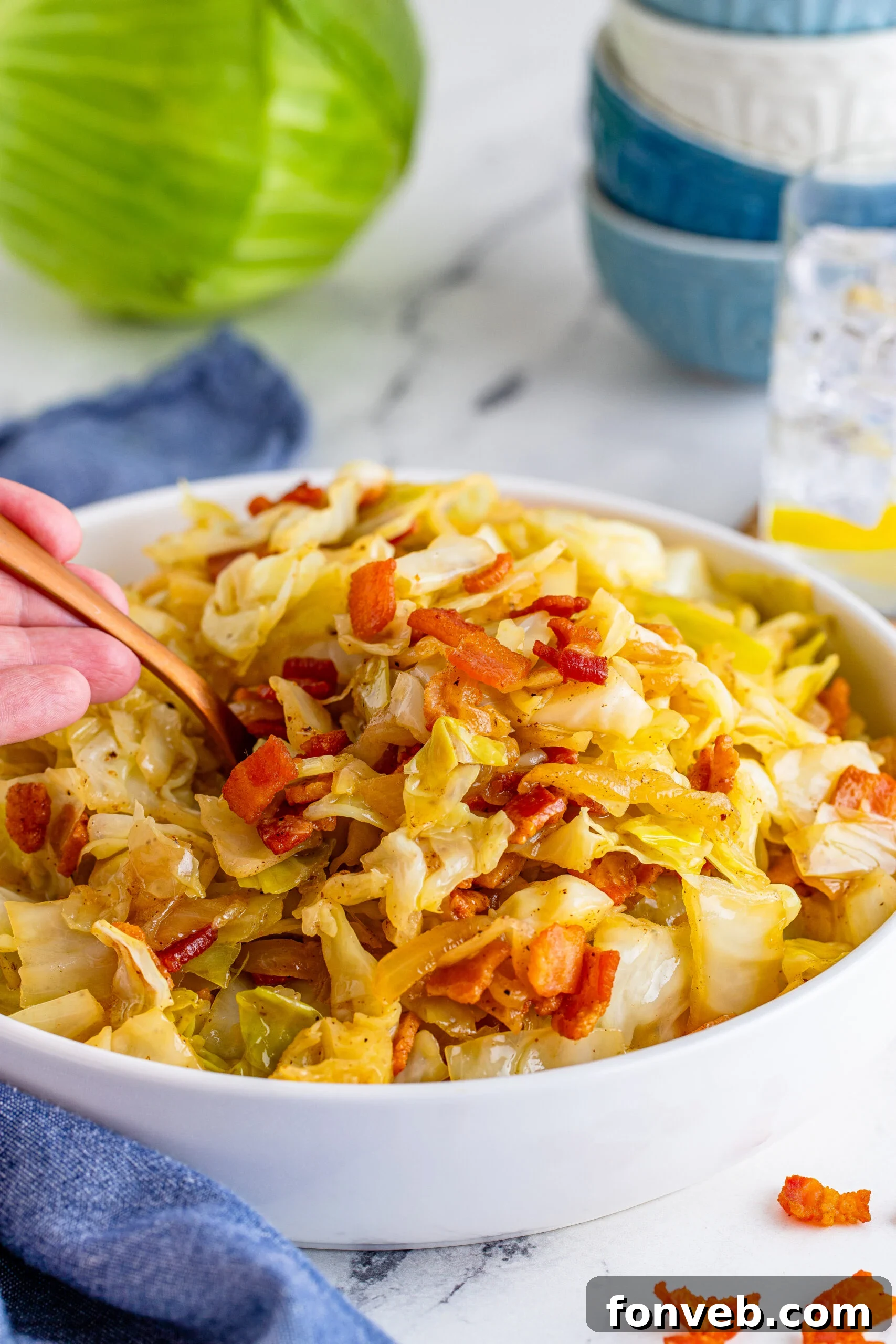 Fried Cabbage in a white bowl with a scoop being removed with a gold spoon. 