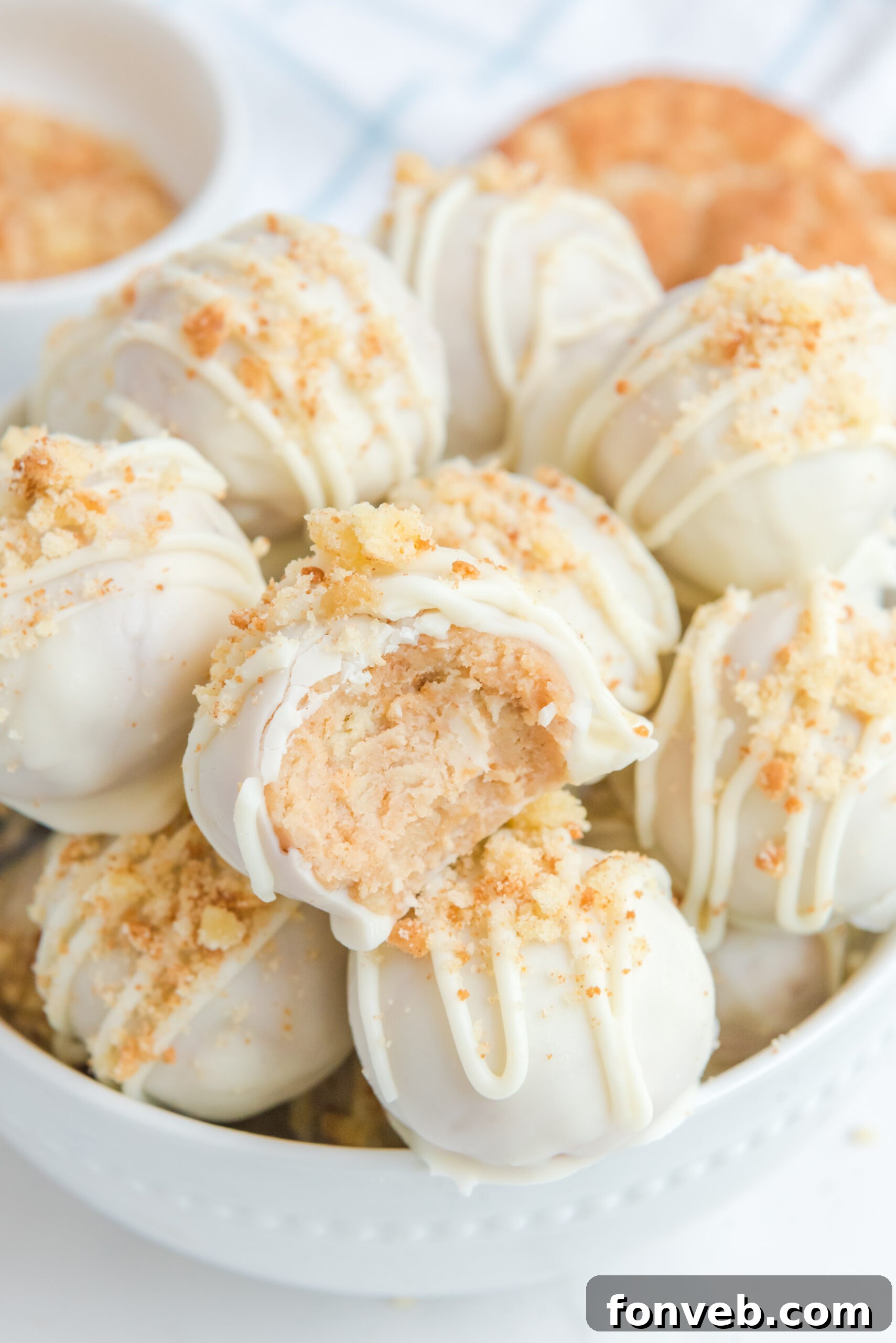 A snickerdoodle truffle stacked on top of other truffles with a bite removed showing the creamy inside.