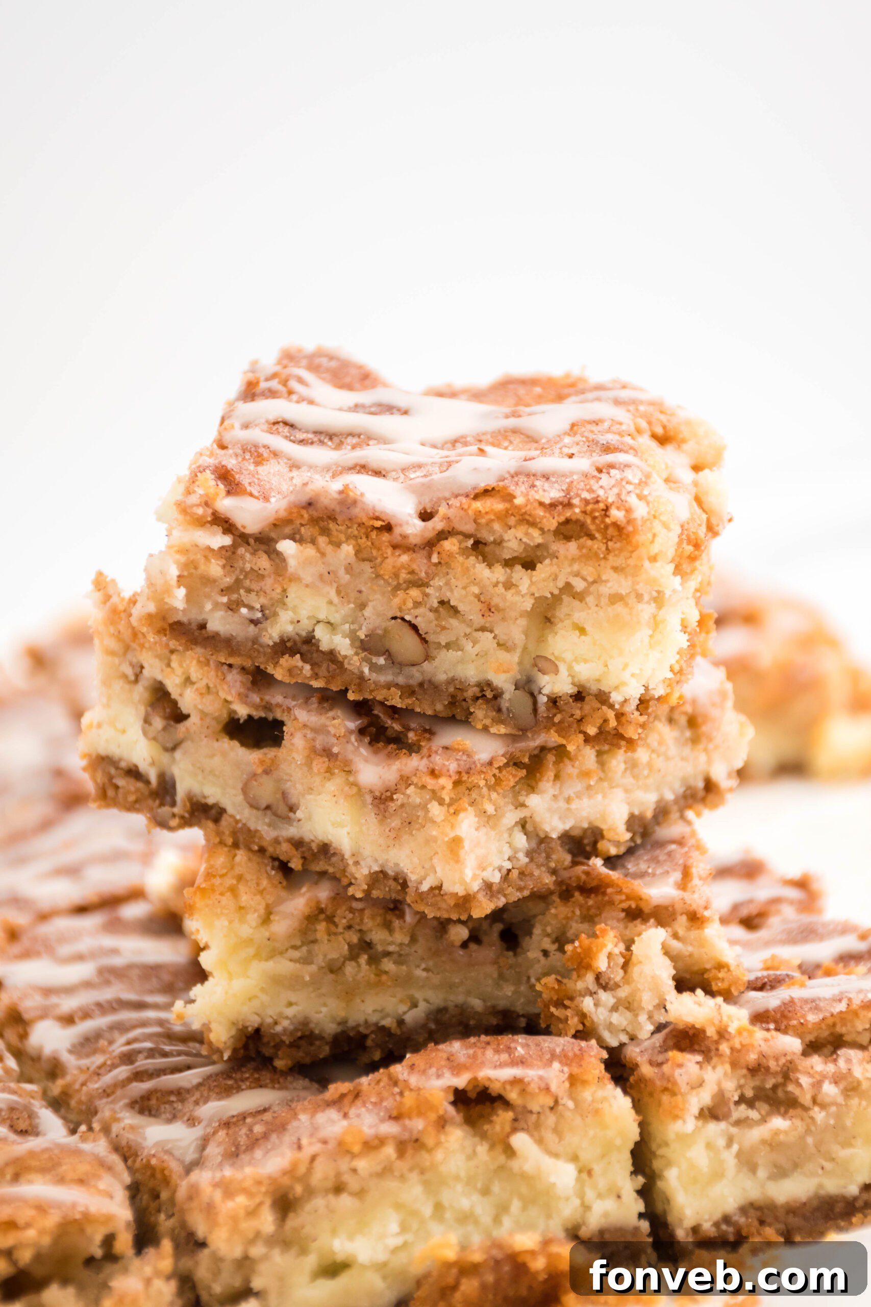 Three Snickerdoodle Cheesecake Bars stacked on top of each other topped with a glaze drizzle.