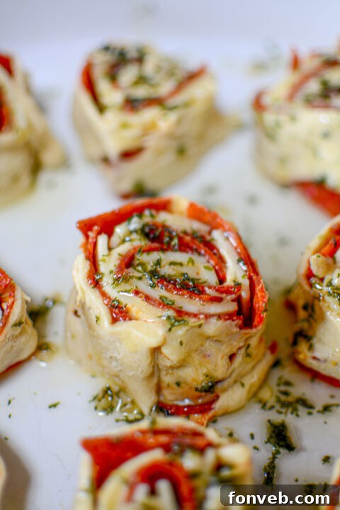 Swirled Pizza Bites 12 Golden-brown pizza pinwheels baking in the oven, cheese bubbling.