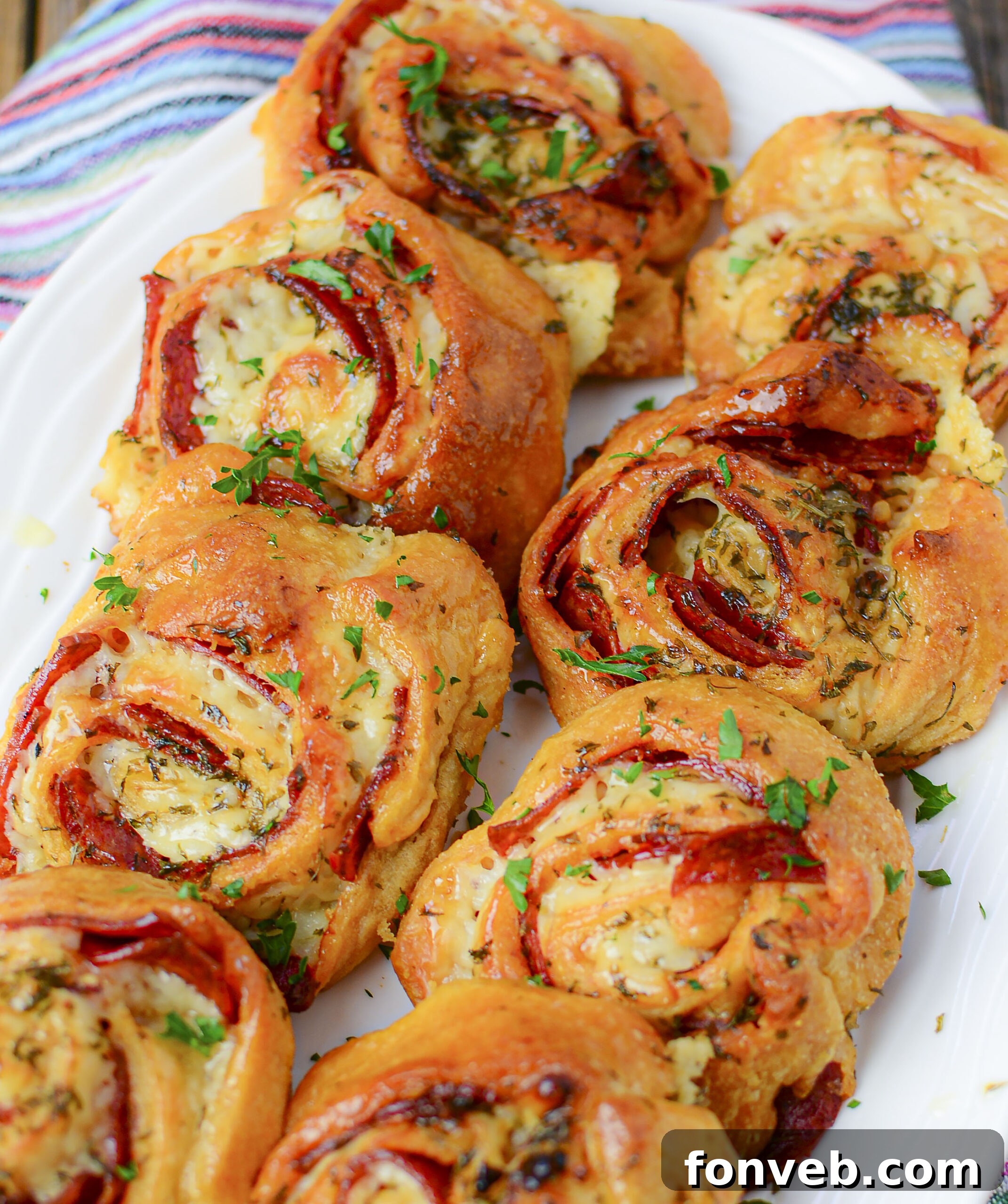 Swirled Pizza Bites 16 Overhead shot of freshly baked pizza pinwheels with a side of marinara dipping sauce.