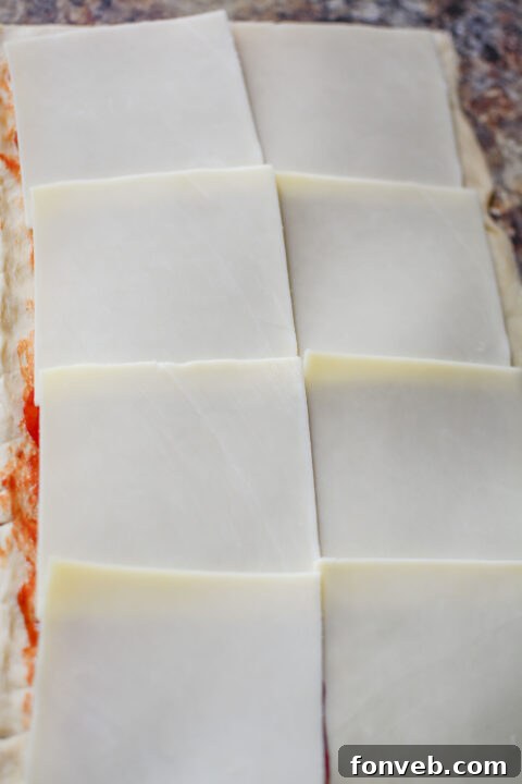 Swirled Pizza Bites 8 Close-up of crescent roll dough with pizza sauce spread, ready for toppings.