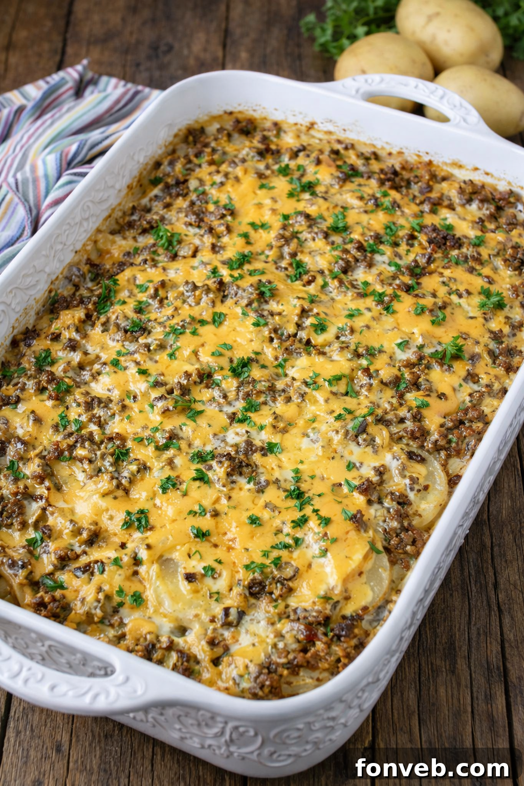 Golden Cheesy Beef and Potato Bake 12 A large, ornate white baking dish filled with Cheesy Ground Beef & Potato Casserole, ready to serve.