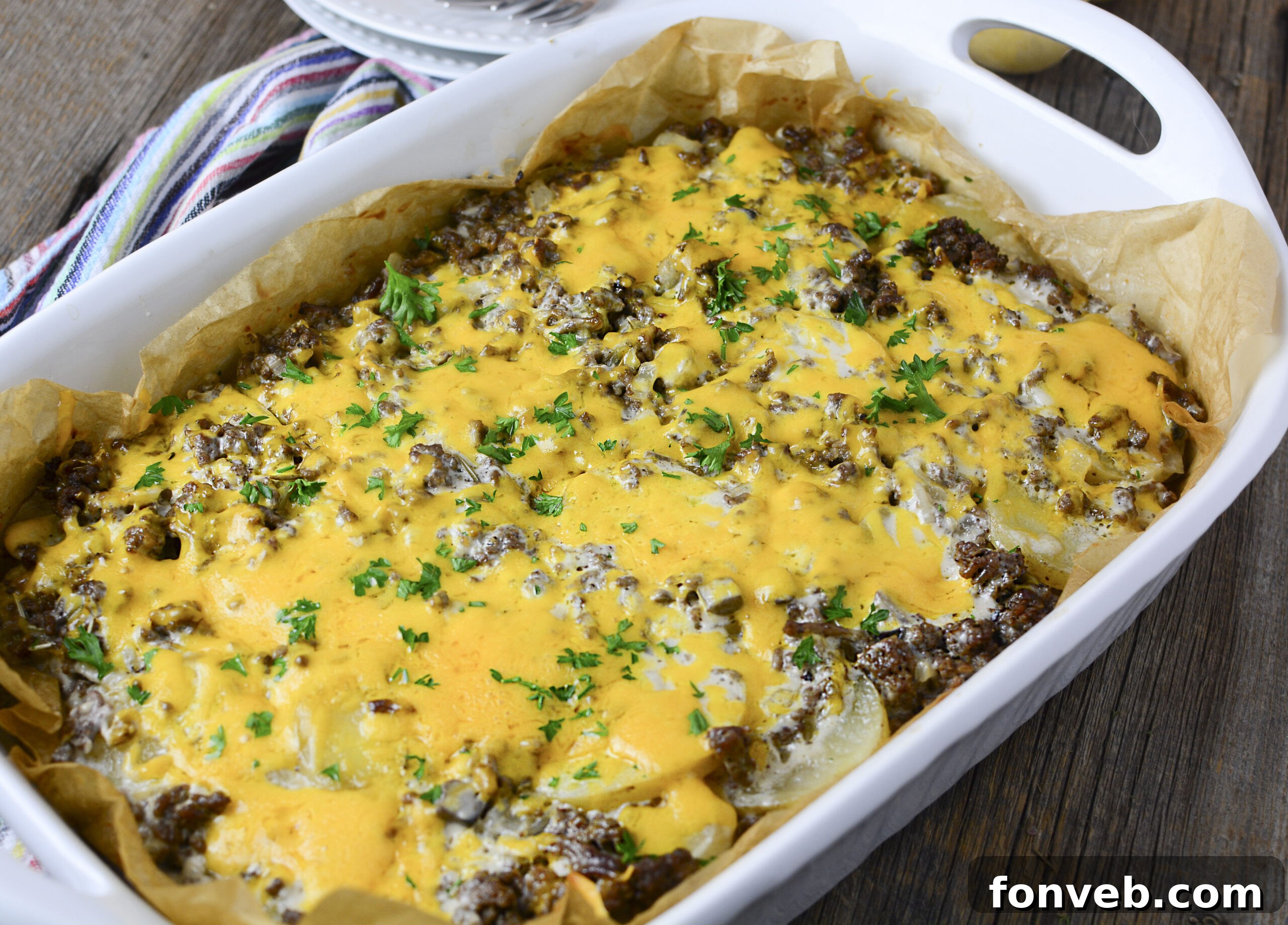 Golden Cheesy Beef and Potato Bake 15 Side view of the layers in a Cheesy Ground Beef and Potato Casserole, smothered in melted cheese within a white baking dish.