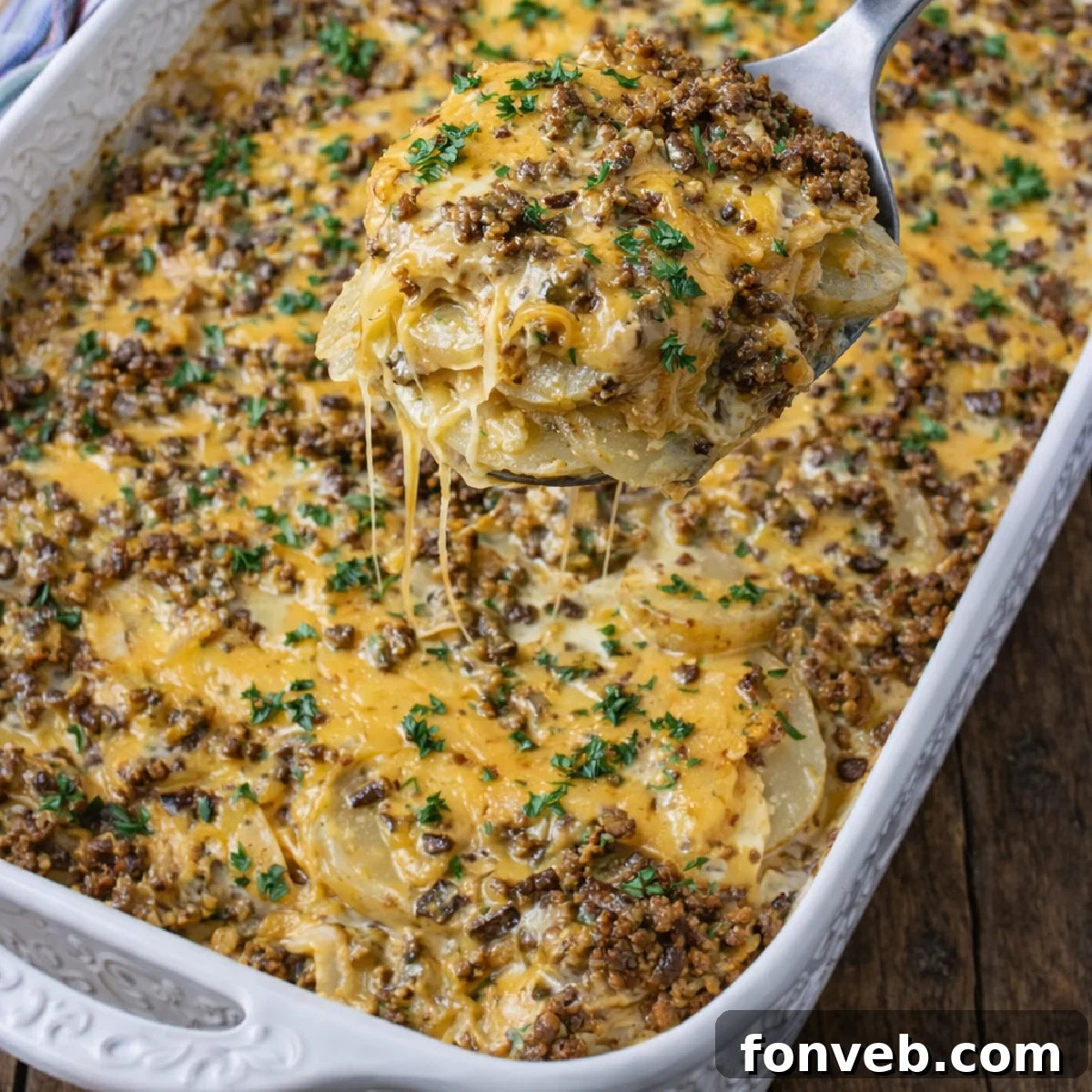 Golden Cheesy Beef and Potato Bake 4 Overhead view of a delicious Cheesy Ground Beef & Potato Casserole baking in a white ceramic pan.