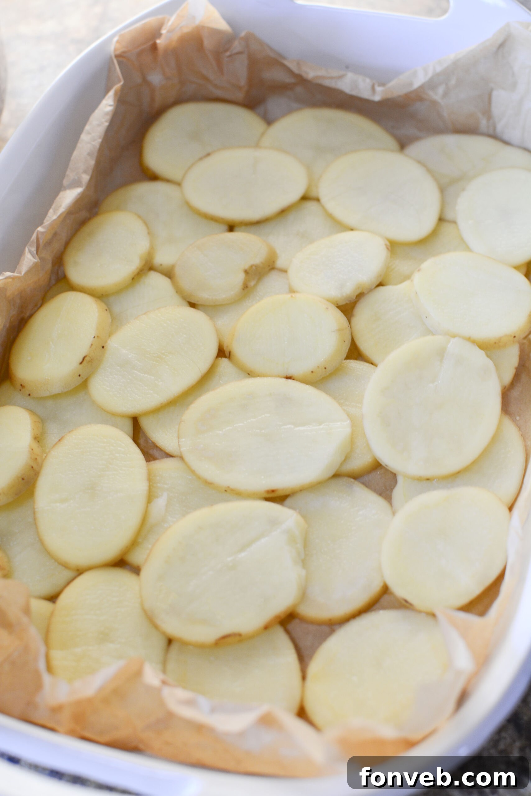 Golden Cheesy Beef and Potato Bake 7 Close-up of thinly sliced potatoes layered in a baking dish, ready for casserole assembly.