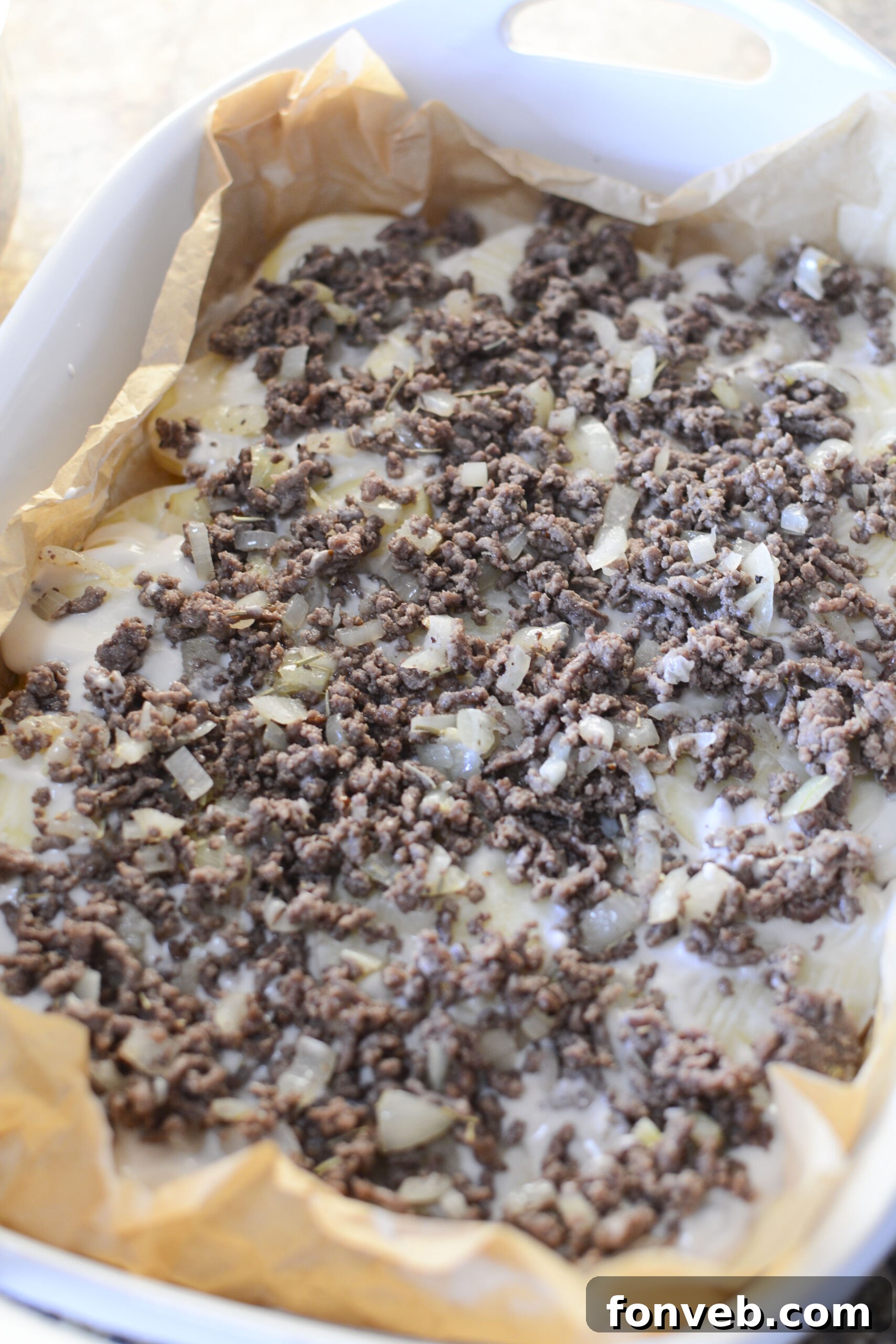 Golden Cheesy Beef and Potato Bake 9 Creamy sauce mixture being whisked in a bowl for the casserole.