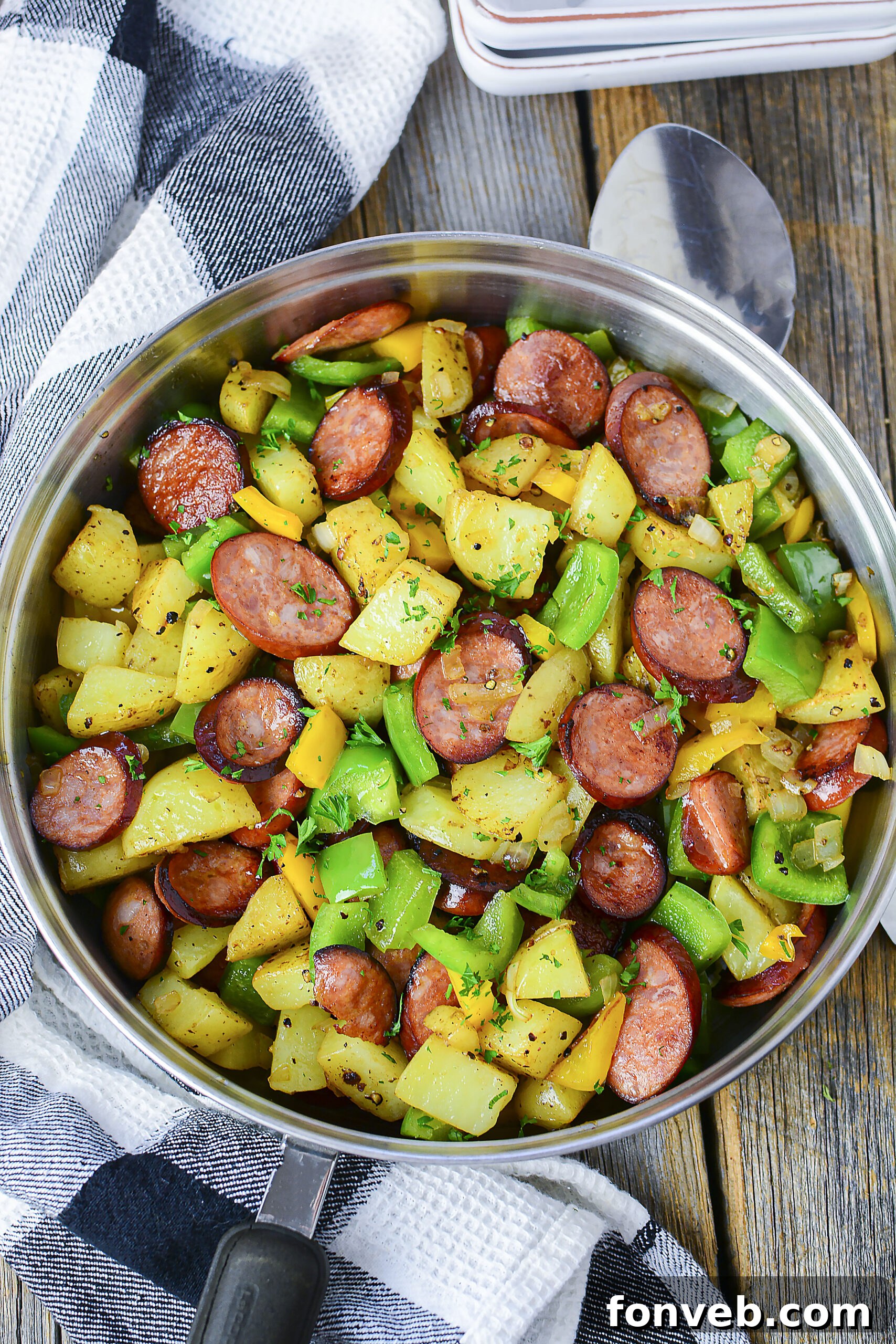 Overhead view of Sausage peppers and potatoes in a silver skillet. 