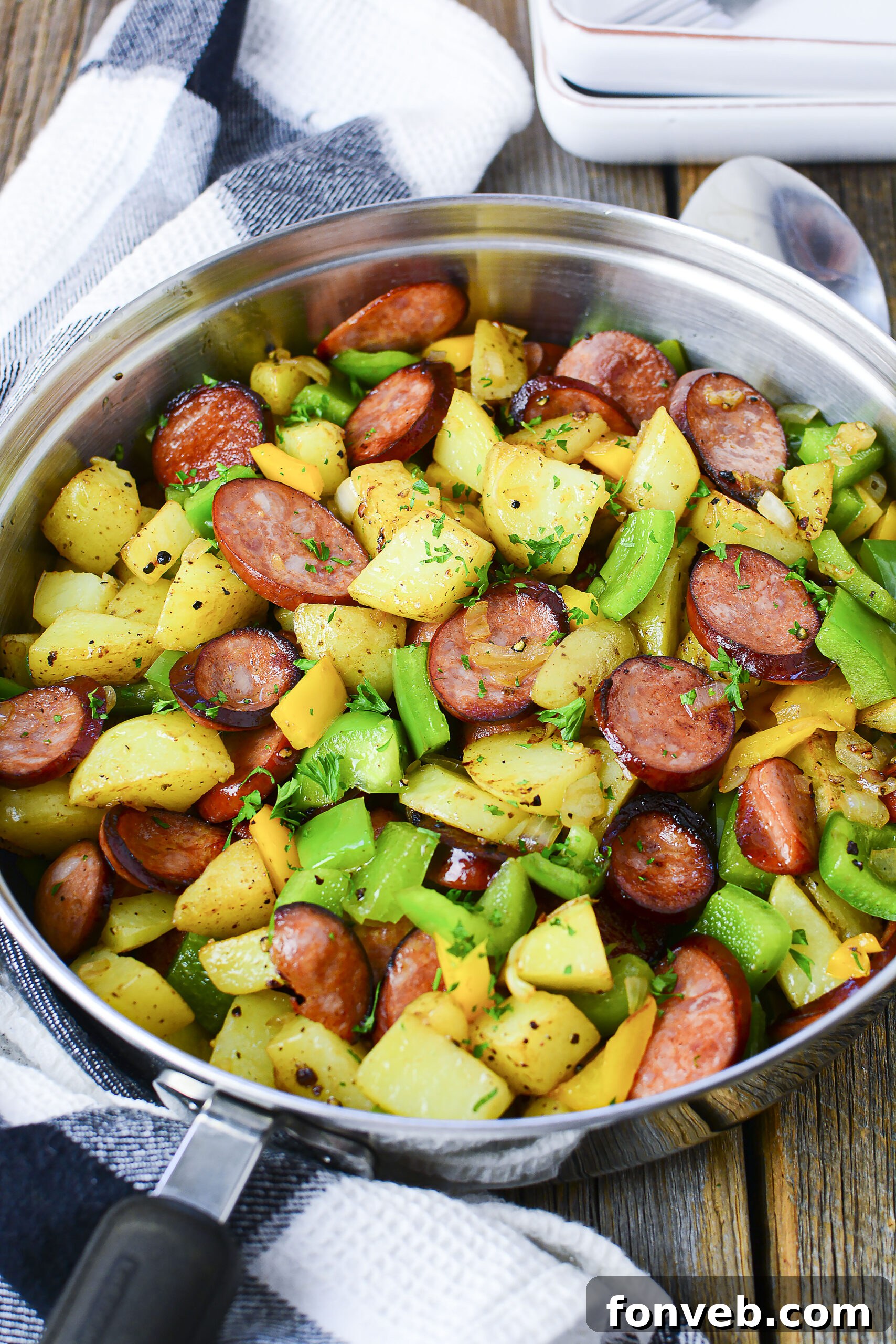 Overhead view of Sausage peppers and potatoes in a silver skillet. 