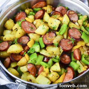 Overhead view of a plated serving of Sausage Peppers and Potatoes with a fork.