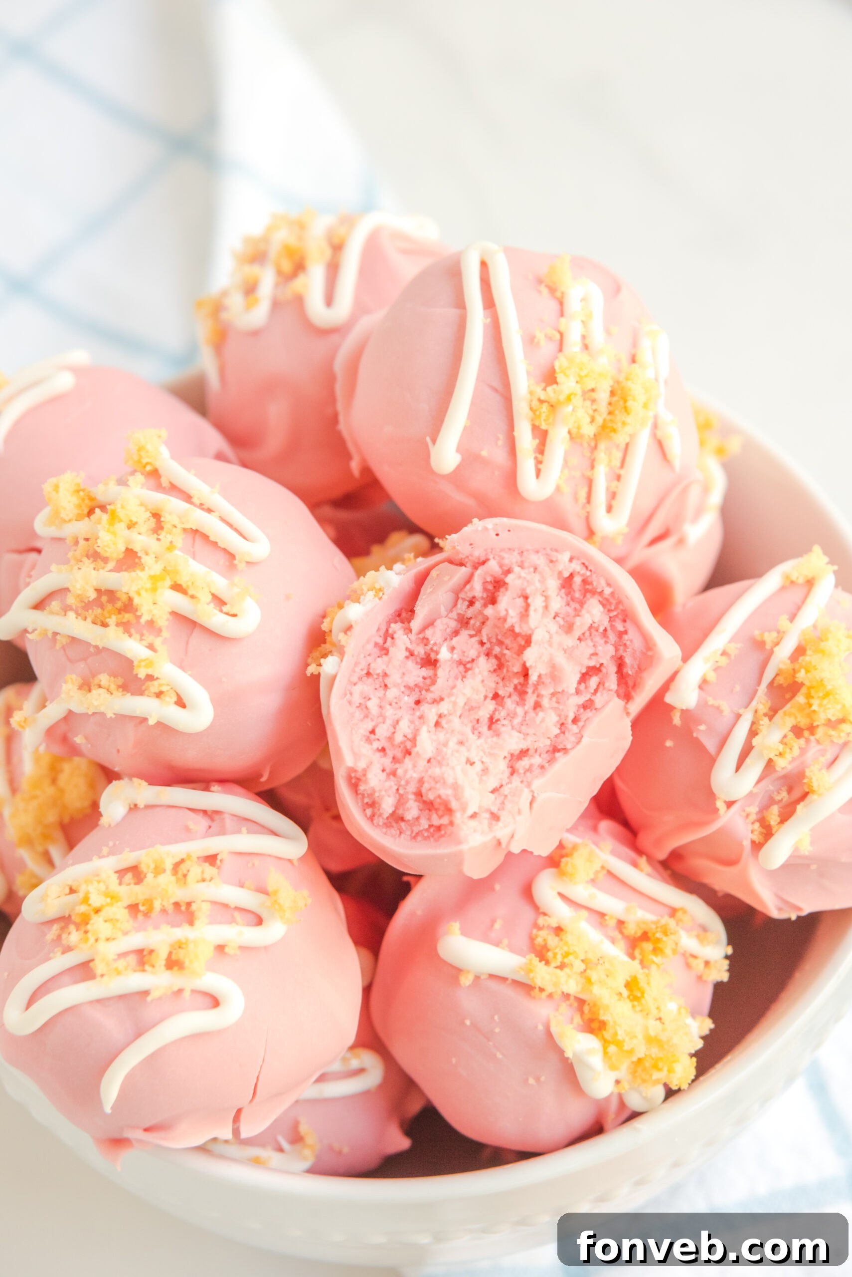 Strawberry truffles stacked on top of each other in a white bowl.