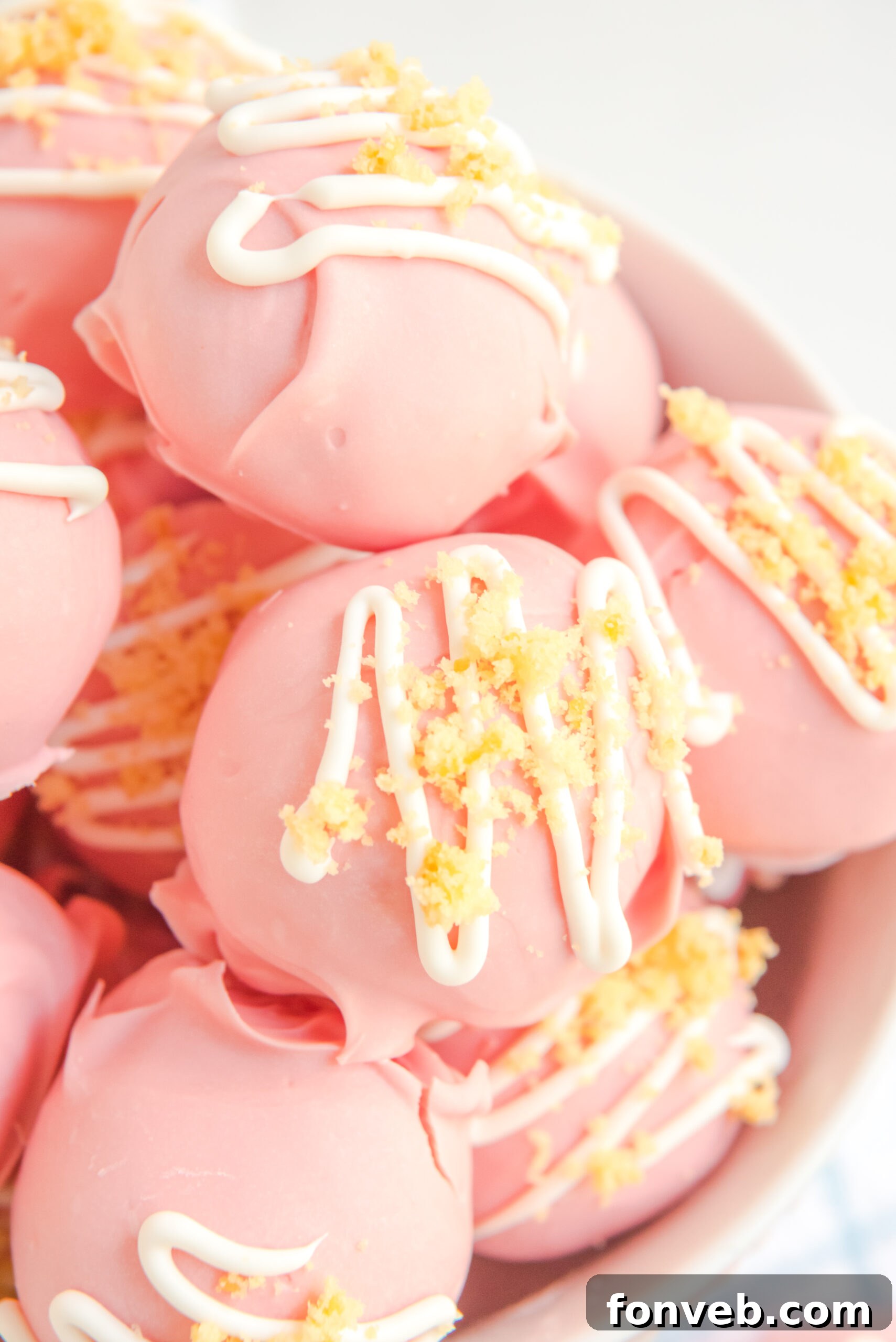 Strawberry truffles stacked on top of each other in a white bowl.