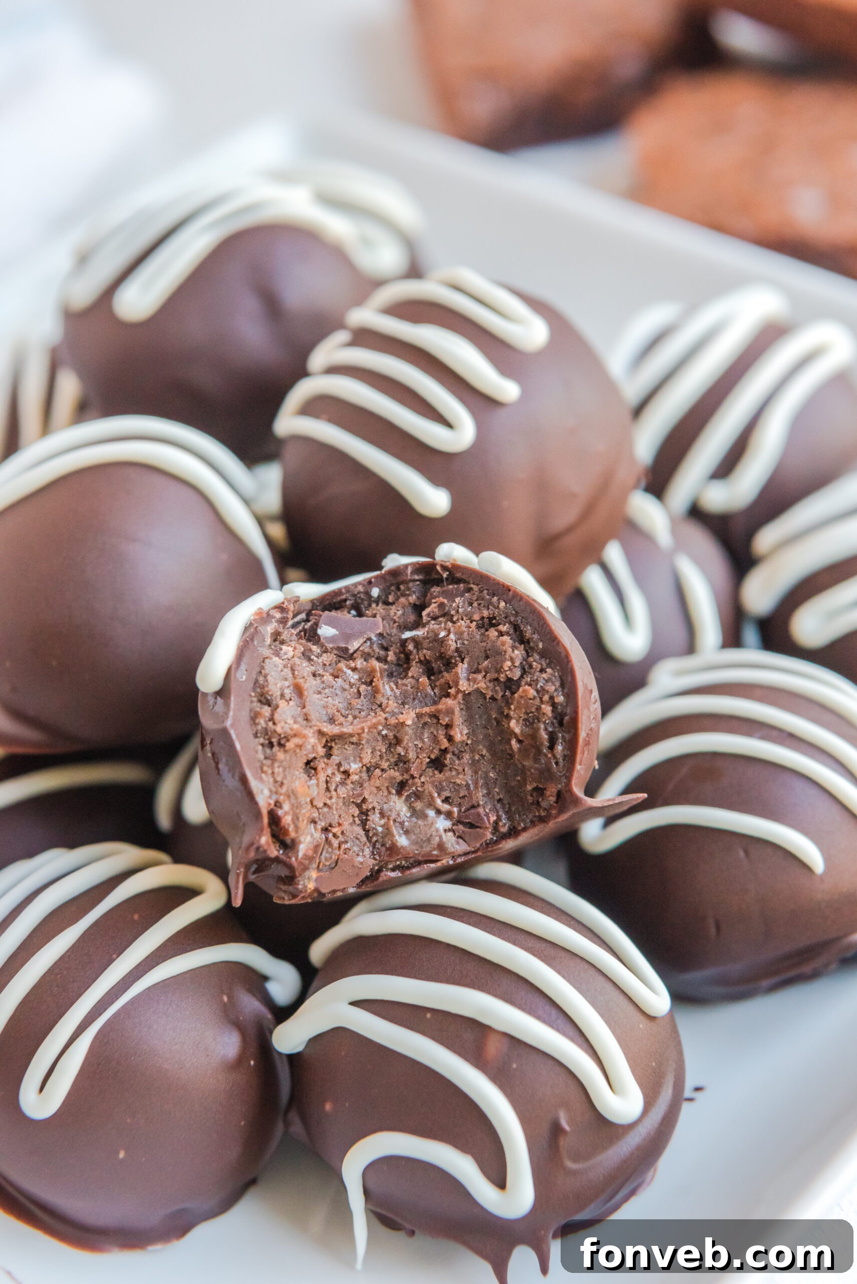 Decadent Brownie Bites 2 Brownie truffles stacked in a white bowl with a bite removed from the top truffle.