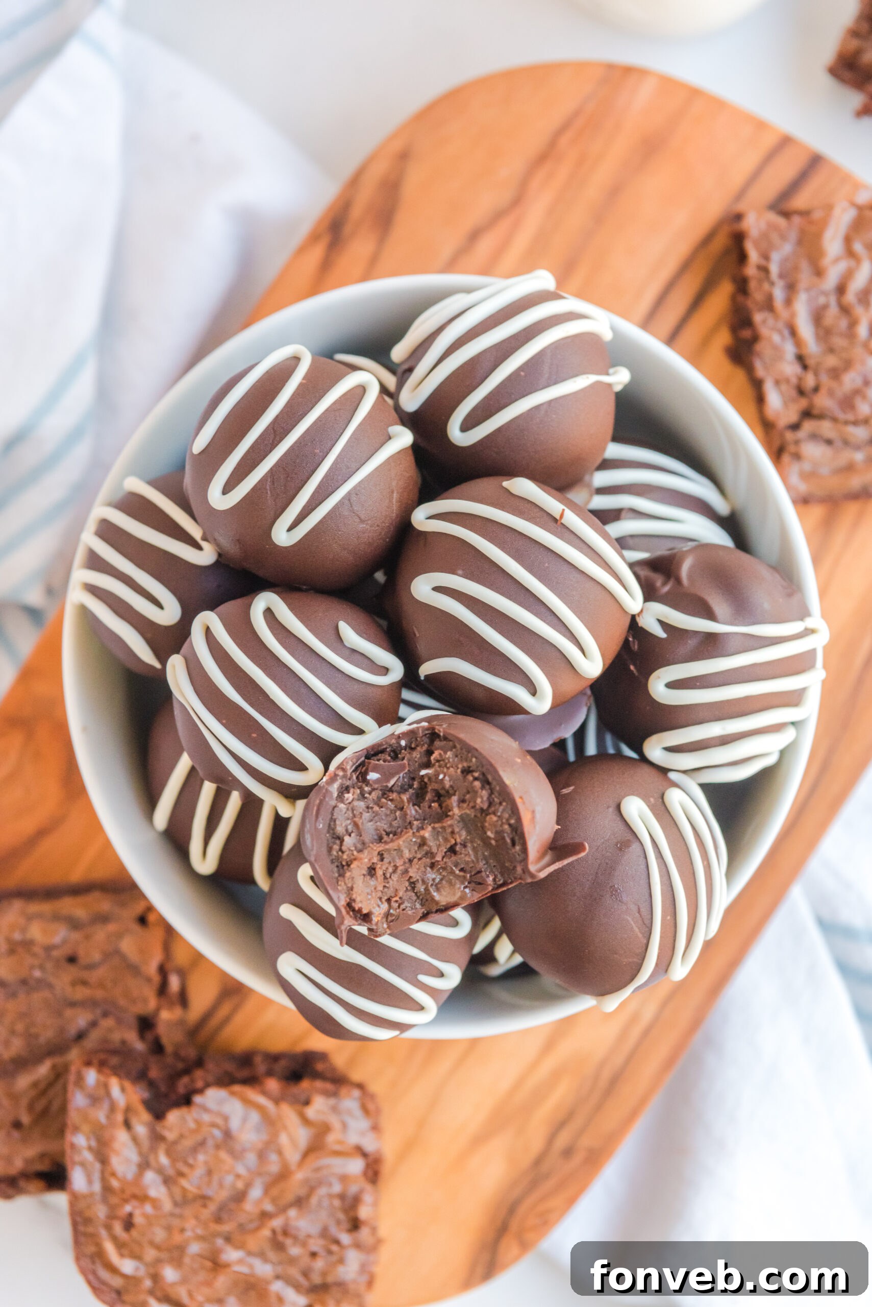 Decadent Brownie Bites 16 Brownie truffles stacked in a white bowl with a bite removed from the top truffle.