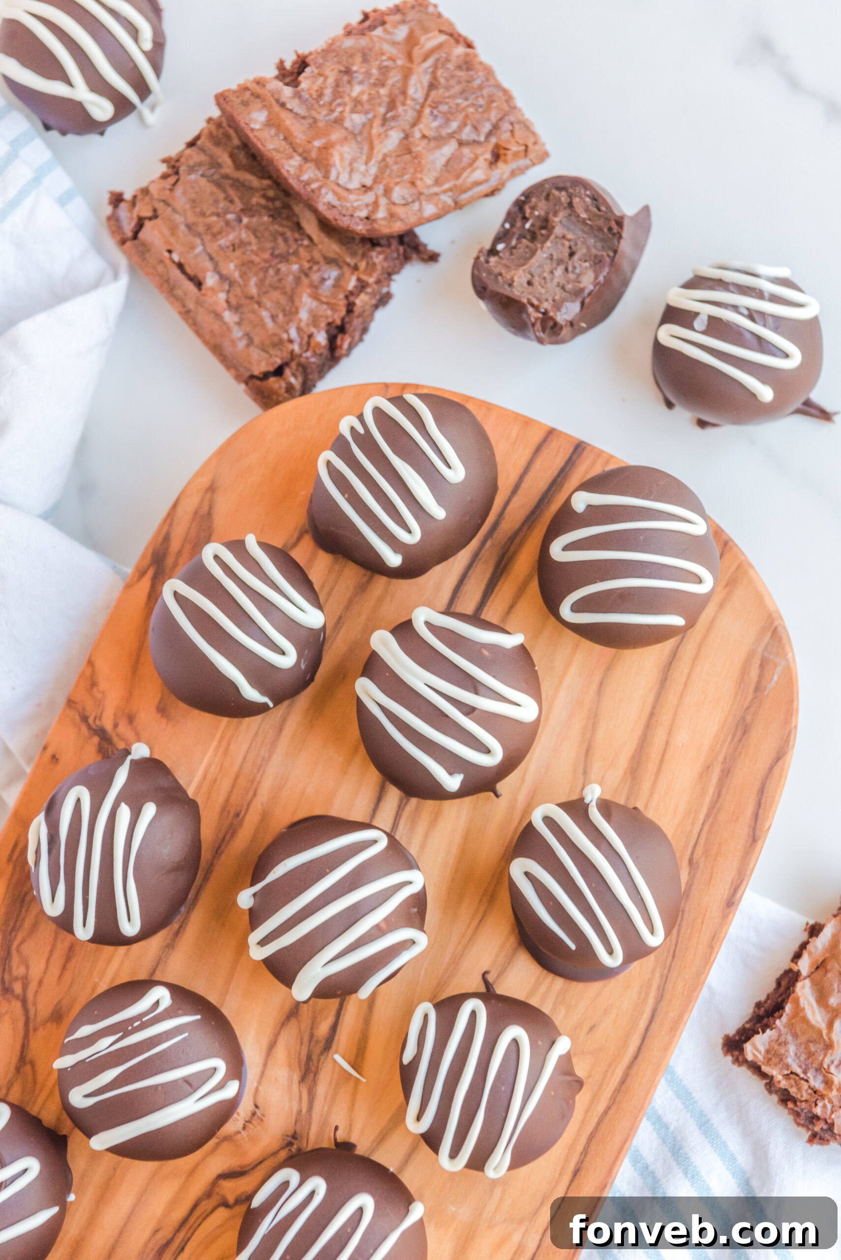 Decadent Brownie Bites 10 Overhead view of brownie truffles on a wooden serving board with brownies in the background.
