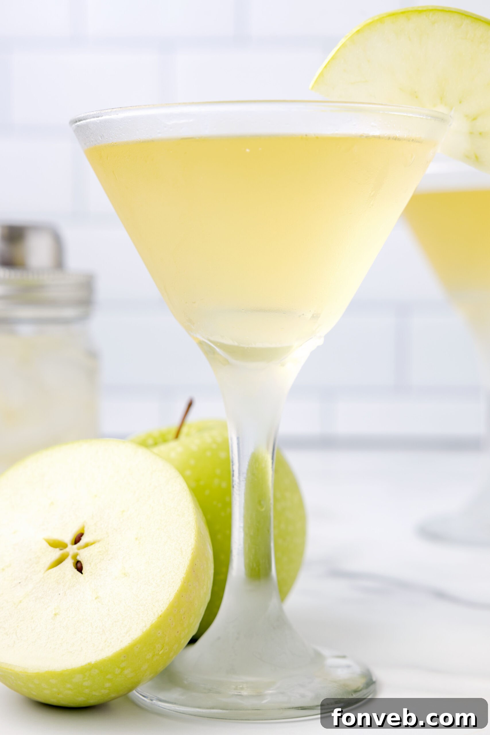 Side view of a vibrant green Appletini in a chilled martini glass, elegantly garnished with a fresh, thinly sliced green apple.