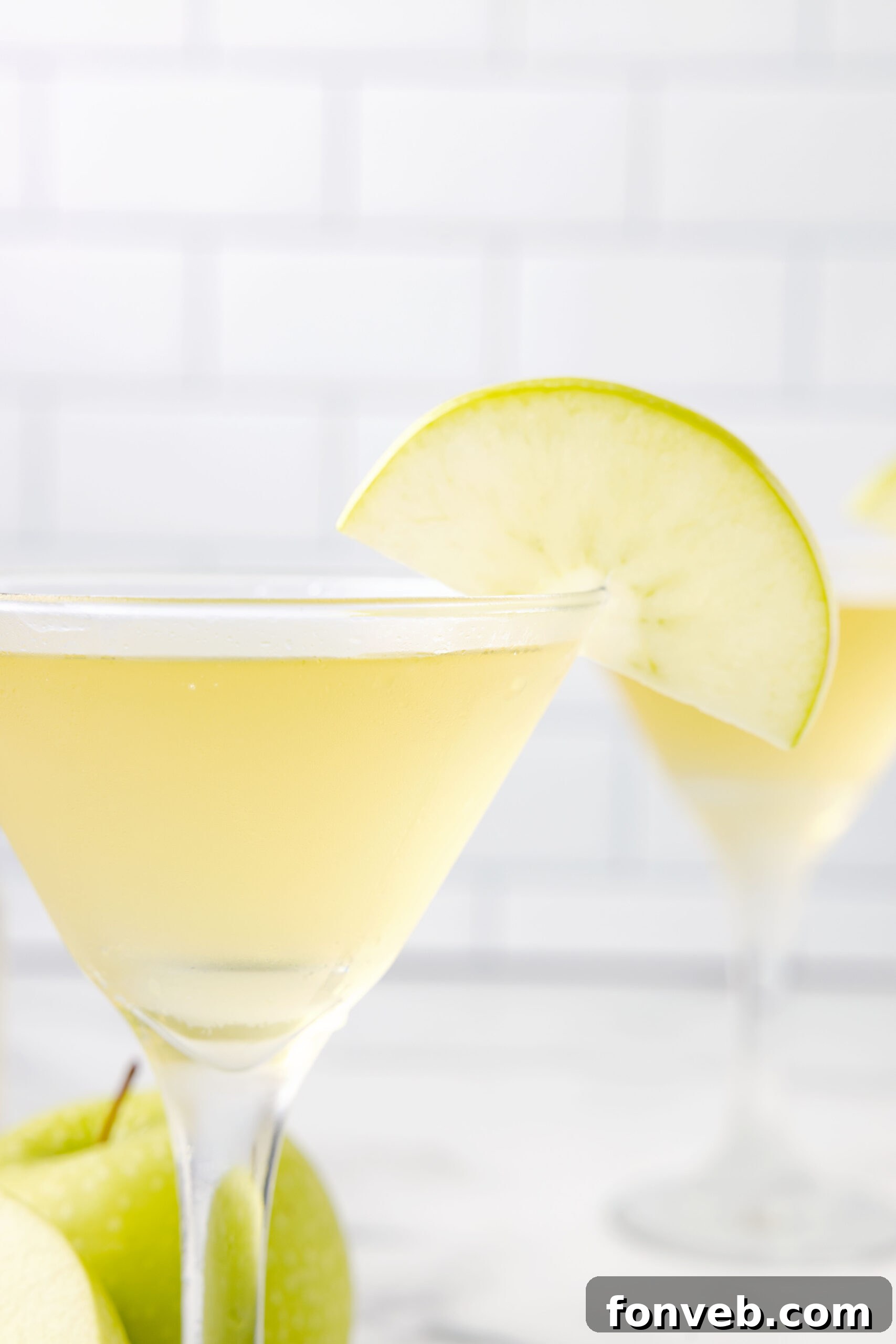 A close-up view of multiple Appletinis in martini glasses, each beautifully garnished with a sliced apple, ready for serving.
