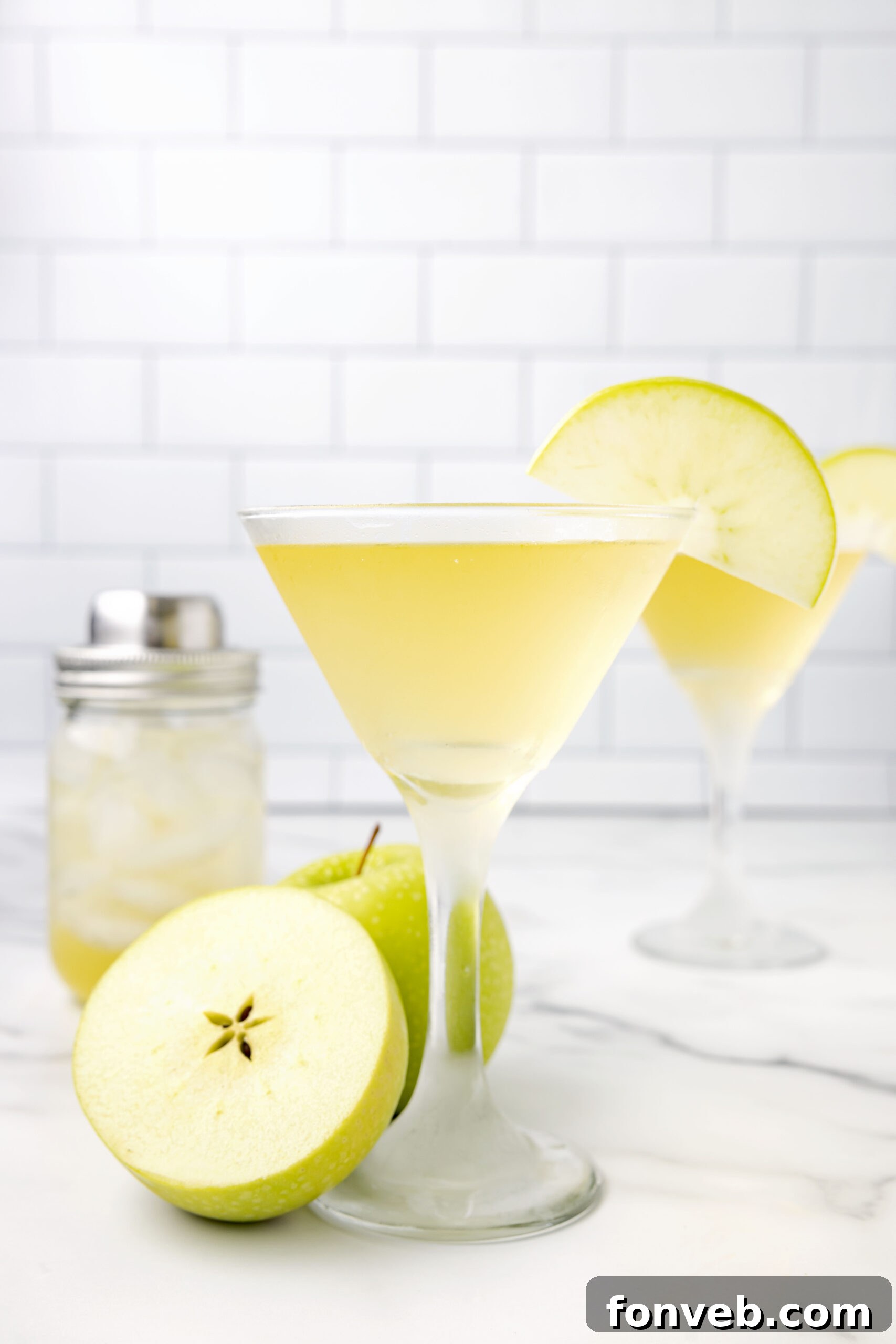 Side profile of an Appletini in a martini glass, garnished with a single apple slice.