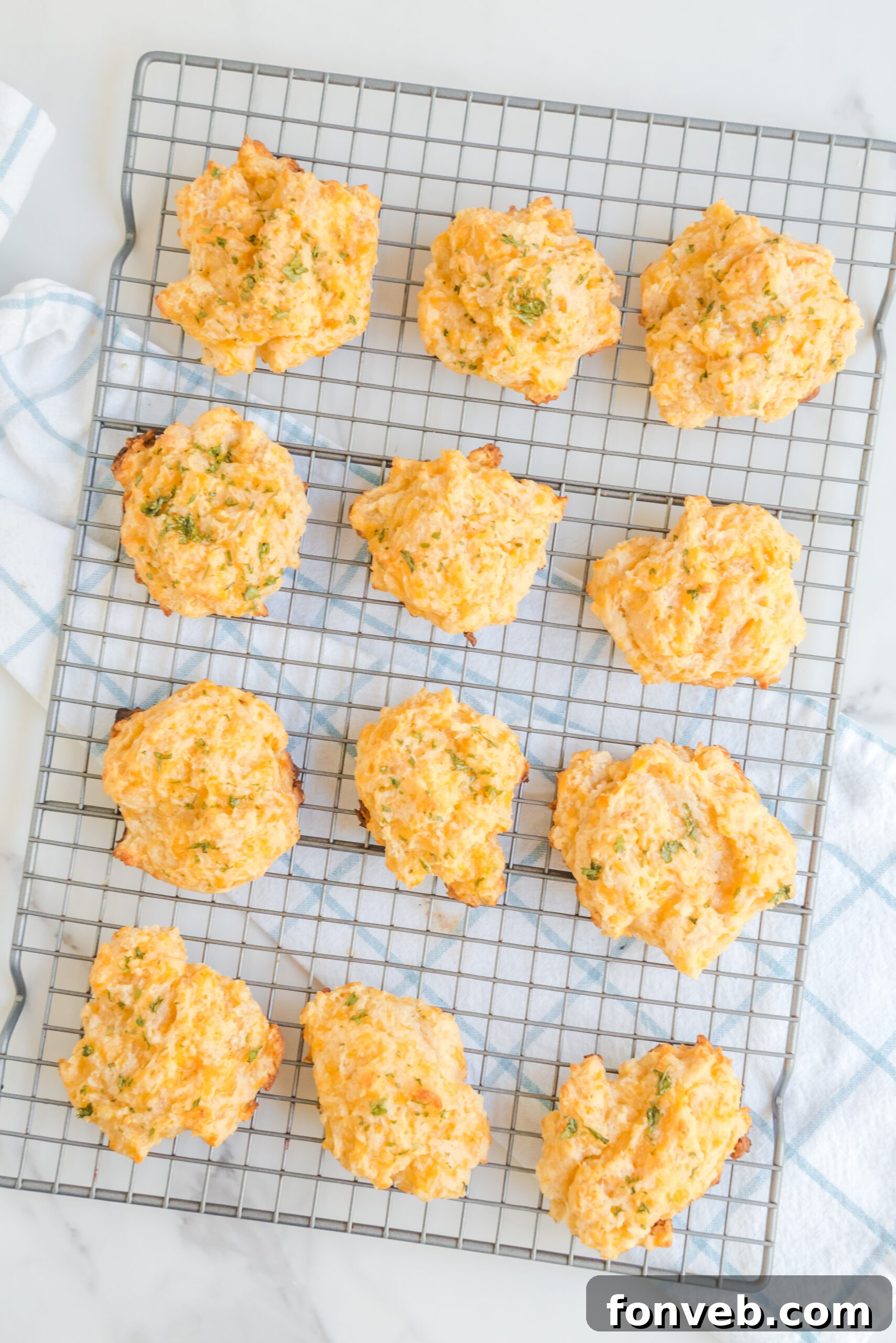 Overhead view of several Copycat Red Lobster Cheddar Bay Biscuits cooling on a wire rack, steam gently rising