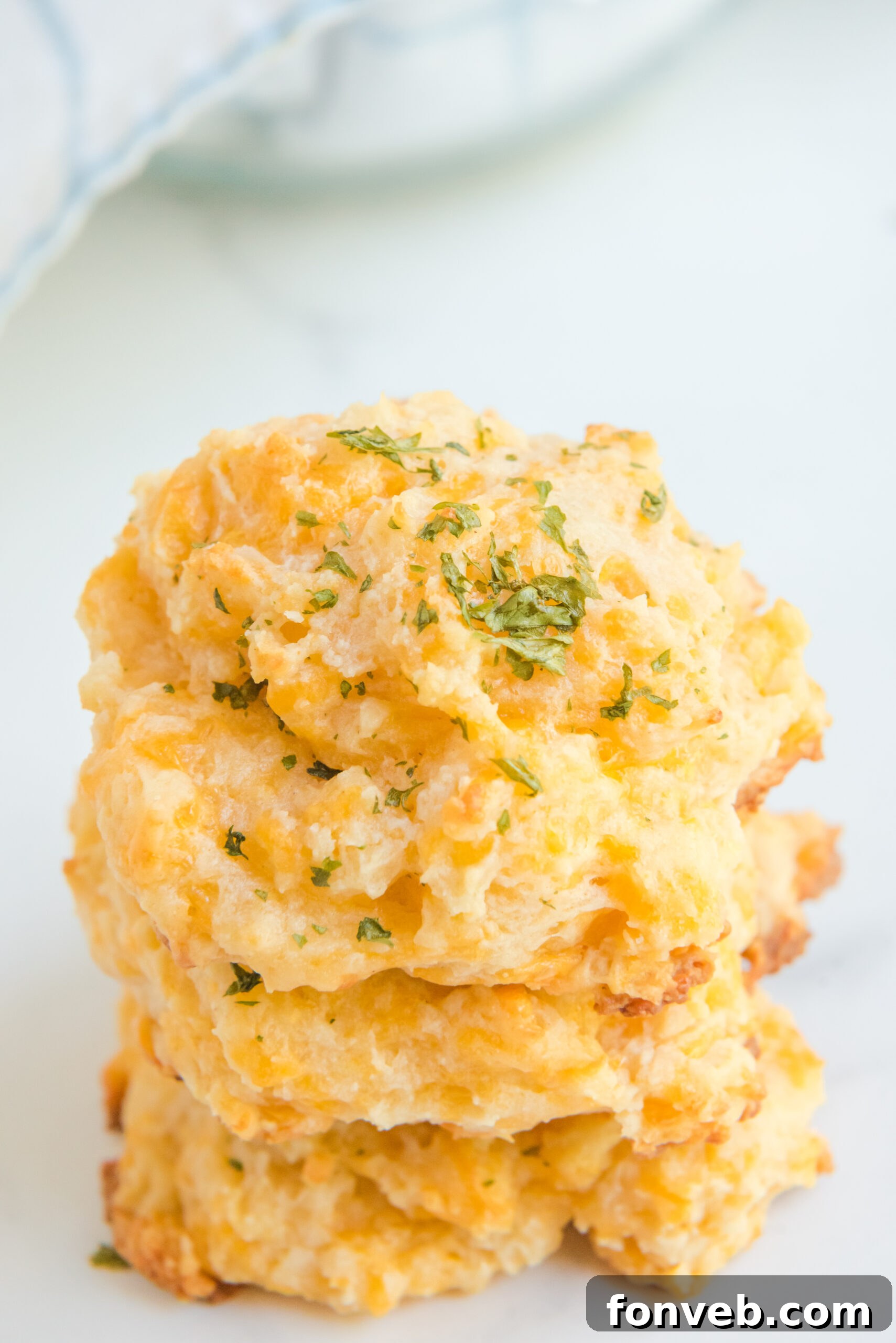 Side view of three perfectly golden Copycat Red Lobster Cheddar Bay Biscuits stacked, showcasing their fluffy texture