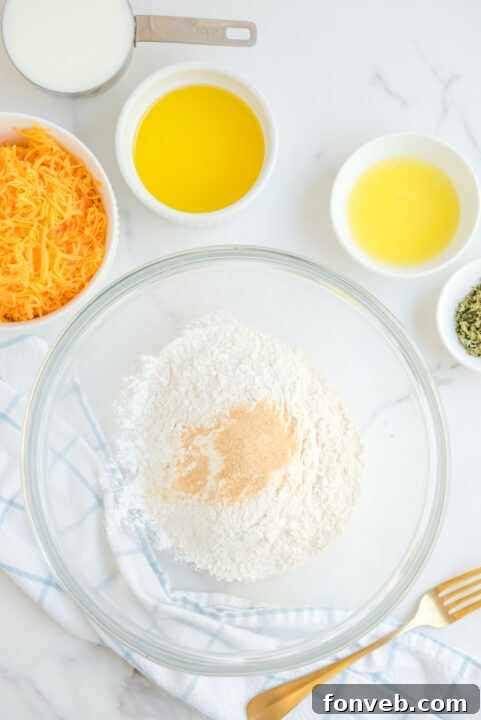 A hand scooping biscuit dough onto a baking sheet