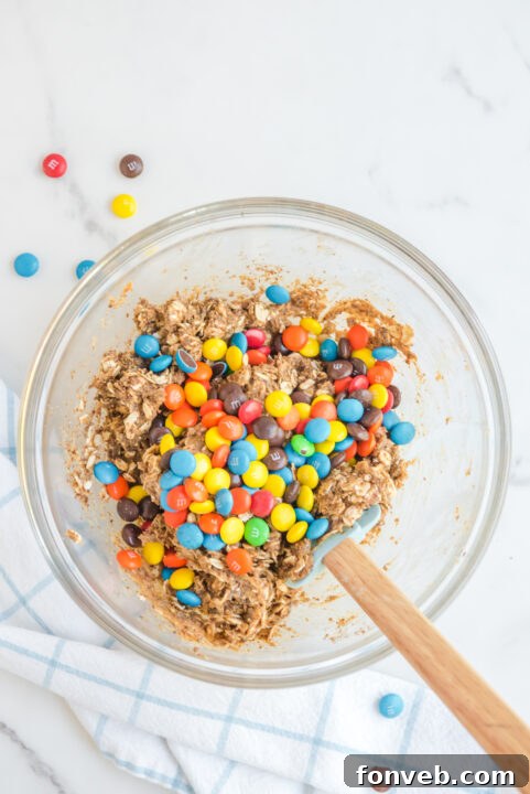 Rolled No Bake M&M Energy Balls on a parchment-lined sheet.