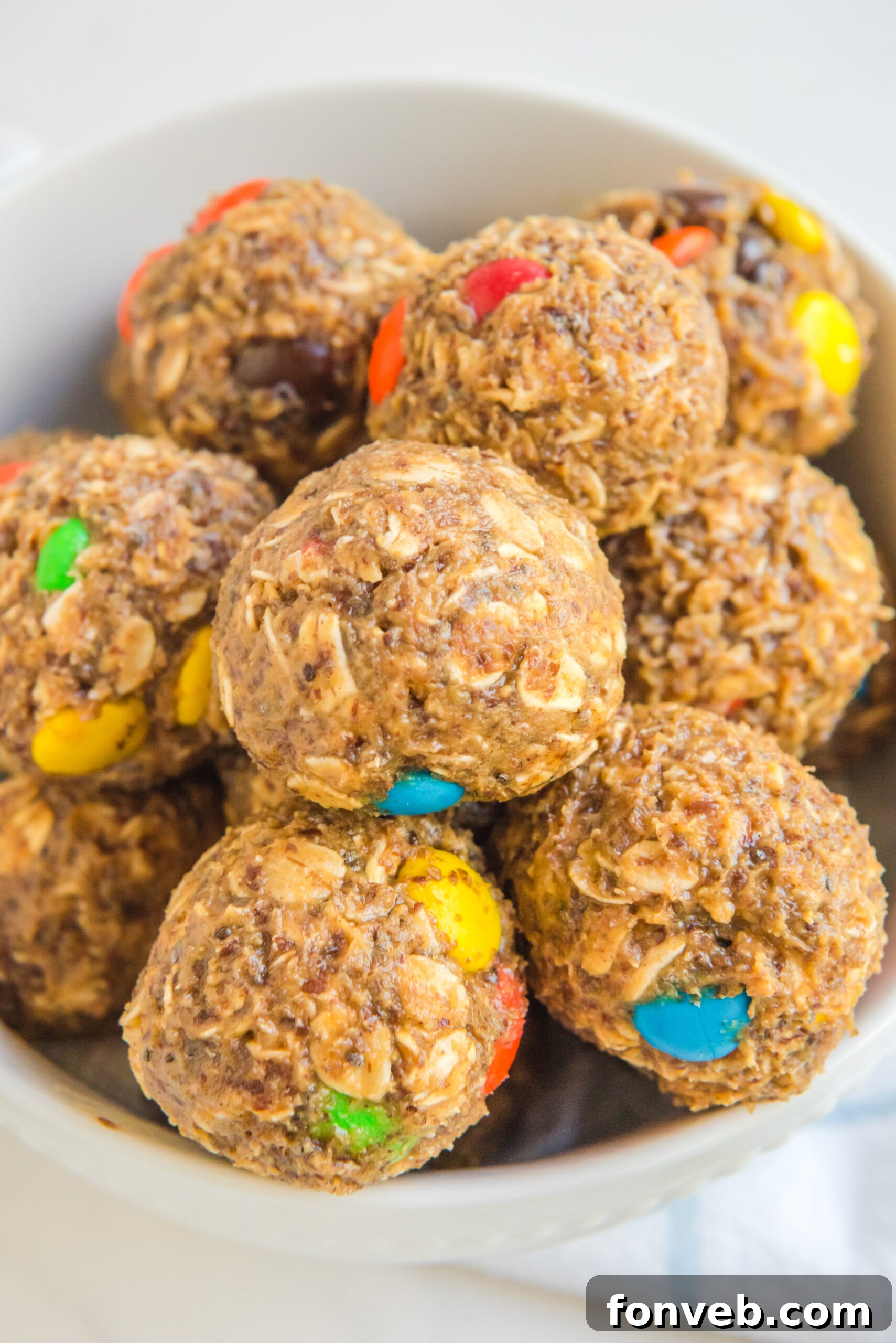 Close up view of No Bake M&M Energy balls in a white bowl.