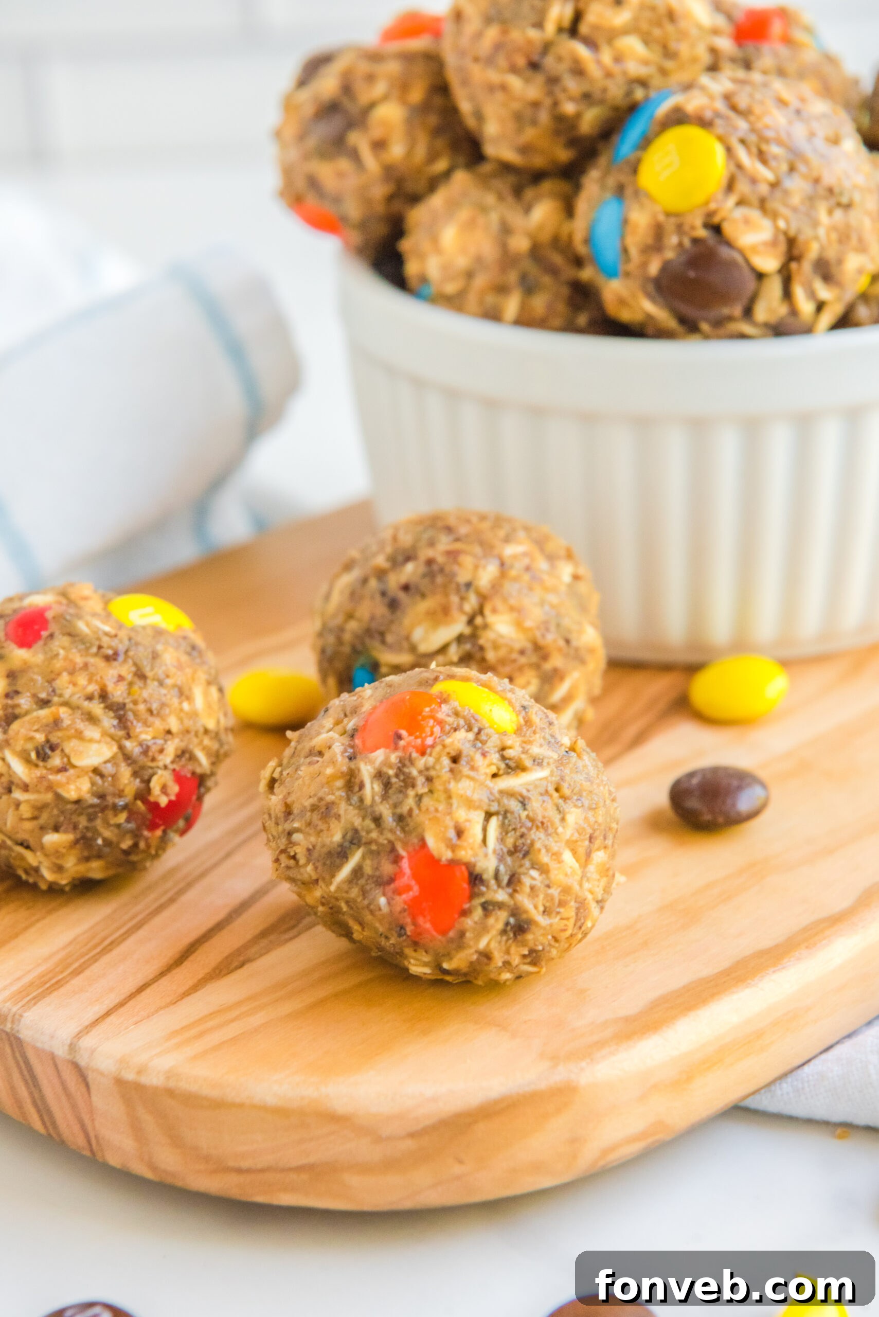 Side view of No Bake M&M Energy Balls on a wooden cutting board. 