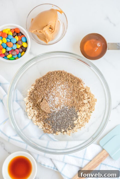 No Bake M&M Energy Balls ready to be rolled on a cutting board.